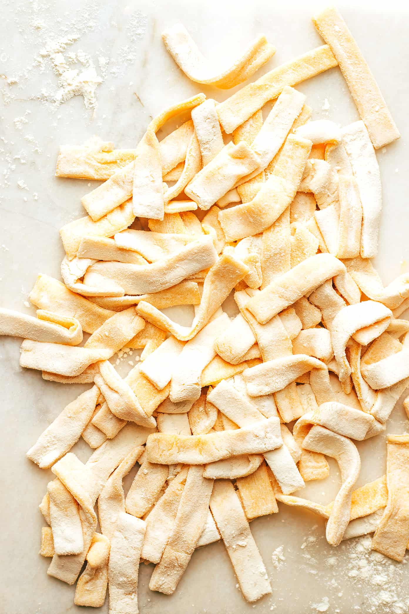 This homestyle egg noodle recipe is incredibly easy to make by hand in just 15 minutes with 4 basic ingredients. Perfect for soups, stews, casseroles and more! | gimmesomeoven.com Homemade Egg Noodles on Marble Cutting Board