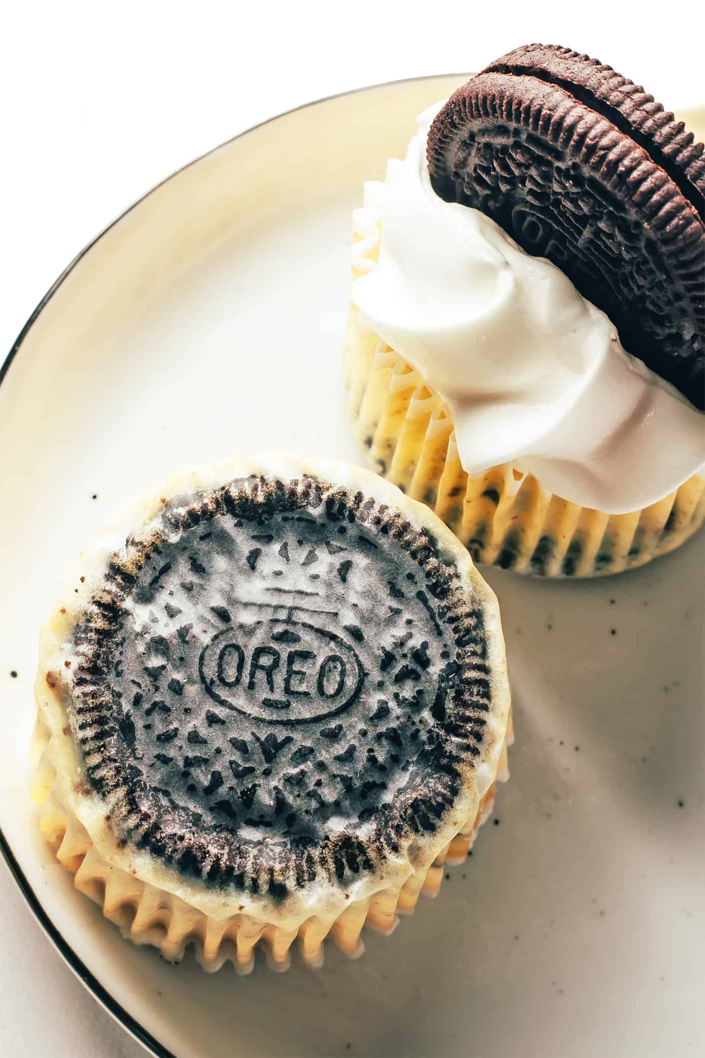 These mini Oreo cheesecakes are easy to make with a delicious mix of cookies and cream, featuring a whole chocolate Oreo as the "crust." Such a fun, simple, and delicious make-ahead dessert! | gimmesomeoven.com Oreo showing through the bottom of a cheesecake wrapper