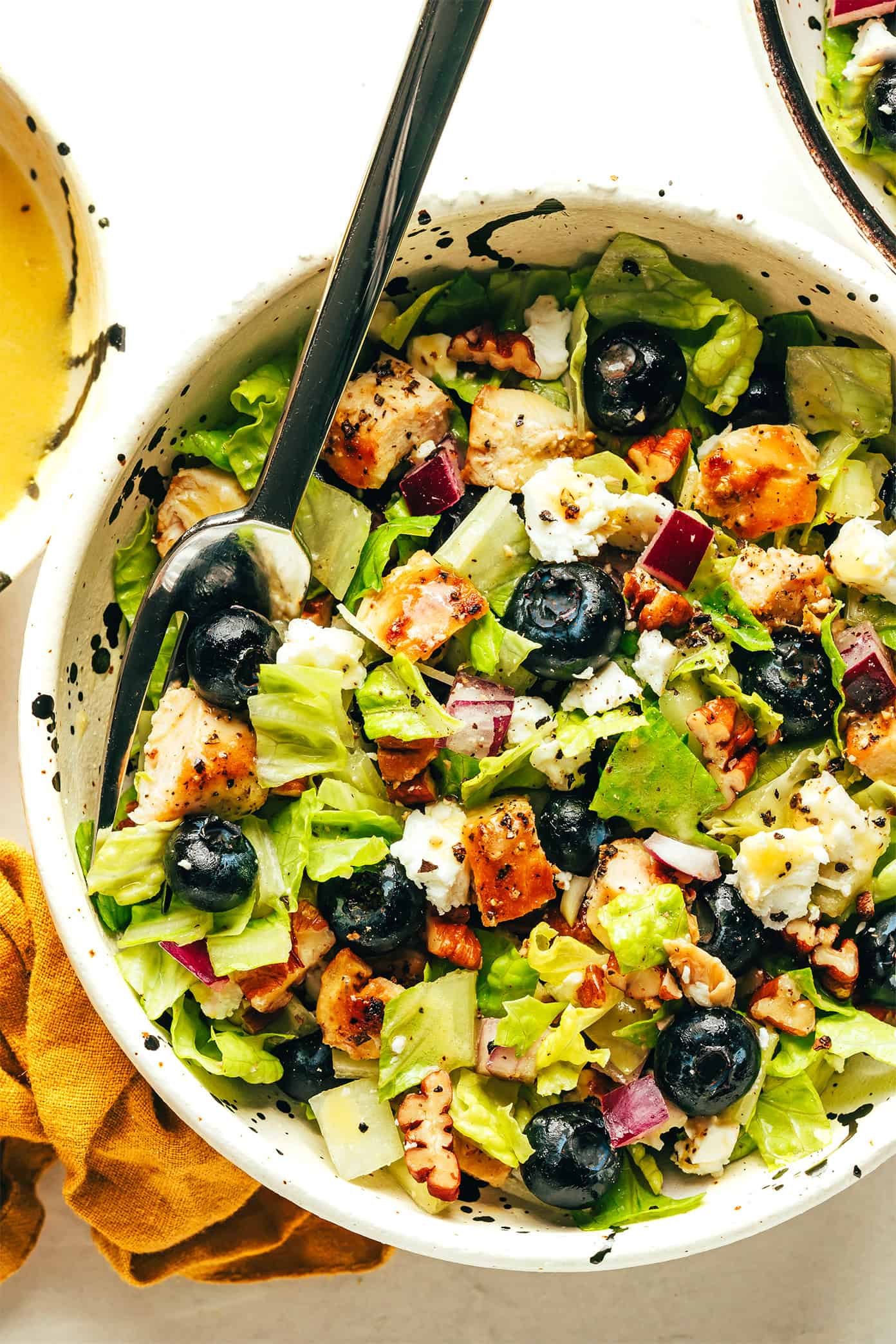 This blueberry chicken chopped salad recipe is loaded up with your choice of greens, tangy feta or goat cheese, diced red onion, toasted pecans, and tossed with a simple lemon vinaigrette. Feel free to swap steak, shrimp, salmon or roasted chickpeas as the protein. Always a delicious and healthy dinner! | gimmesomeoven.com Blueberry salad closeup