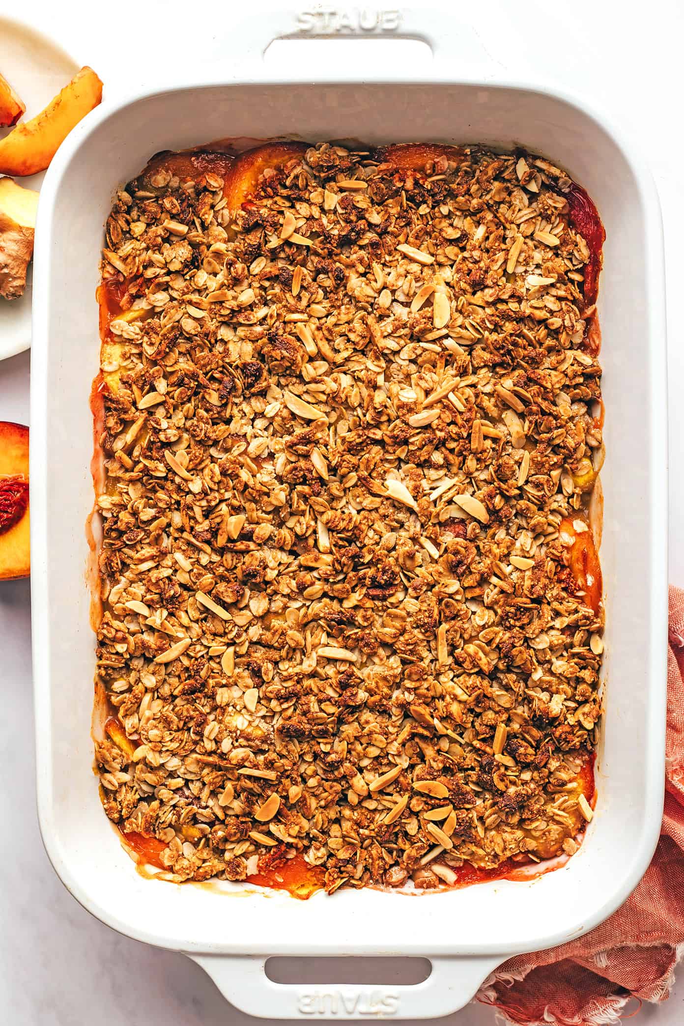 This ginger peach crisp recipe is made with a warm ginger-vanilla peach filling and topped with a crispy almond oat topping. Easy to make, naturally gluten-free and vegan, and SUCH a delicious summer dessert! | gimmesomeoven.com Baked Peach Crisp in Pan