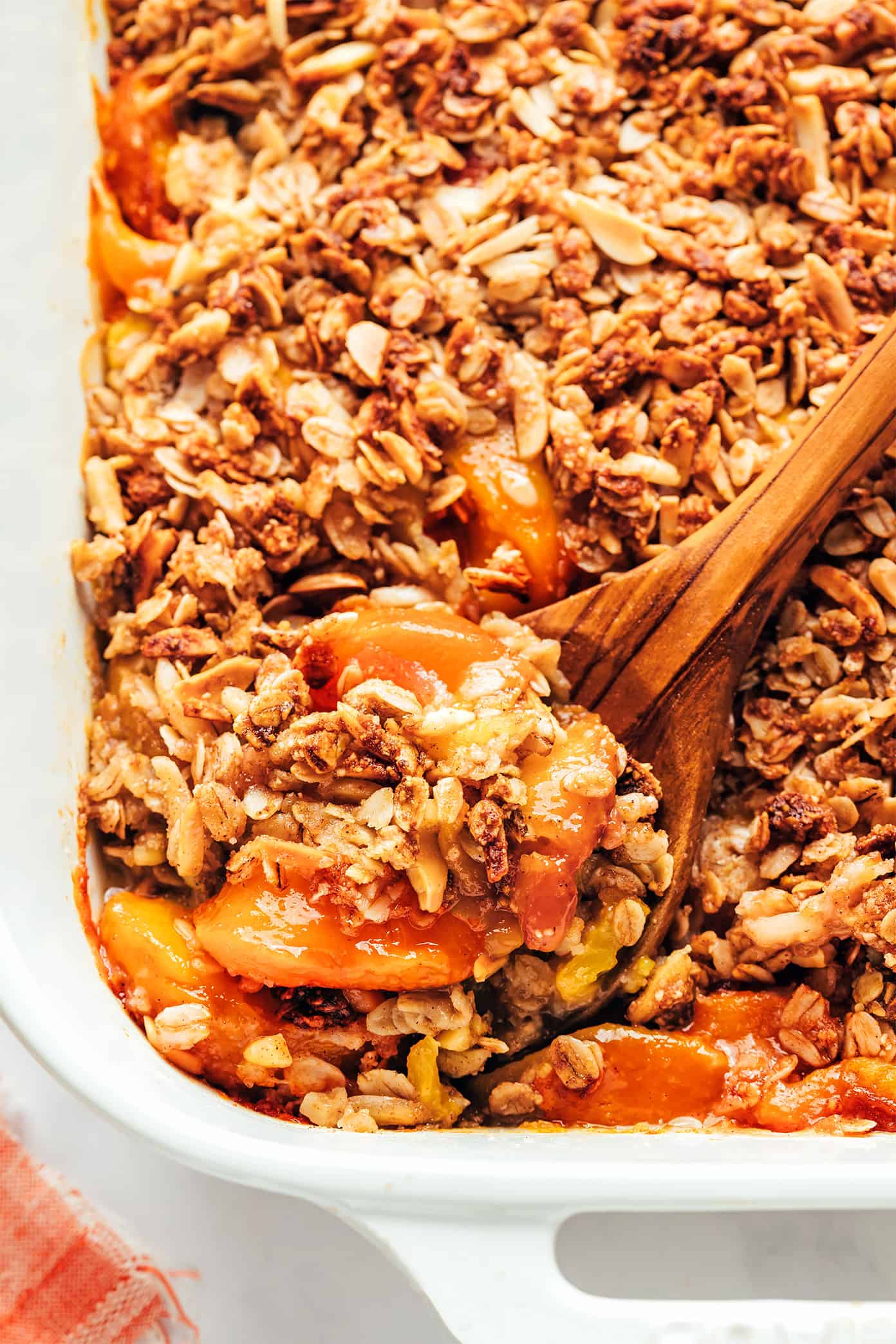 This ginger peach crisp recipe is made with a warm ginger-vanilla peach filling and topped with a crispy almond oat topping. Easy to make, naturally gluten-free and vegan, and SUCH a delicious summer dessert! | gimmesomeoven.com Peach Crisp Closeup with Spoon