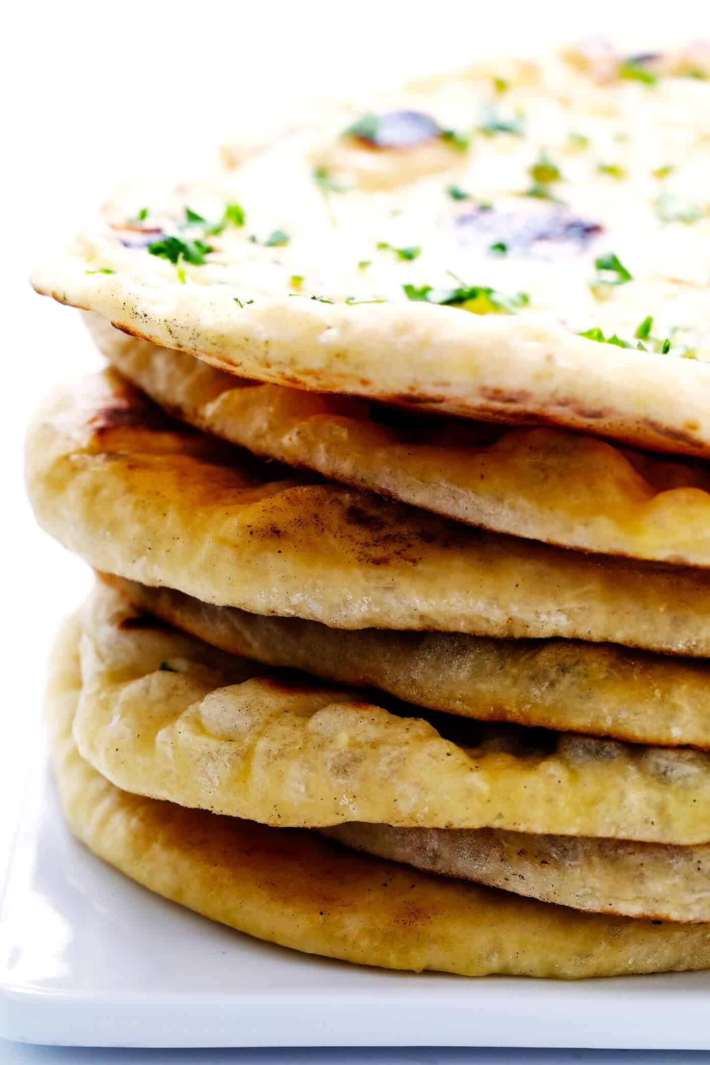 This homemade naan recipe is easy to make, perfectly soft and chewy, and always so delicious. I've included a garlic naan recipe option below too! | gimmesomeoven.com #naan #bread #flatbread #vegetarian #homemade #wrap #garlic Stack of Homemade Naan Bread