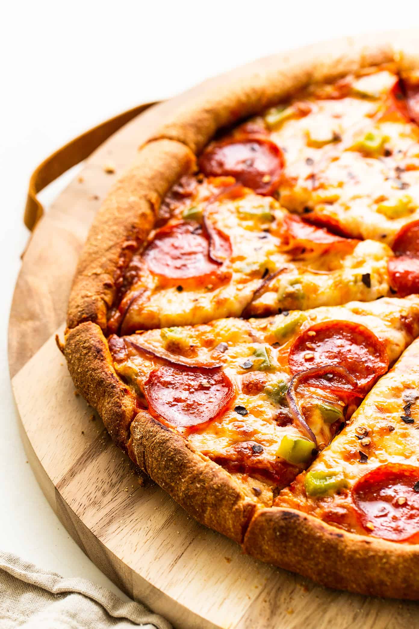 My favorite homemade whole wheat pizza dough recipe is easy to make by hand or with a stand mixer, it's naturally sweetened with a hint of honey, and it's always perfectly chewy and delicious. Feel free to add Italian seasoning, garlic, or Parmesan to your pizza crust too if you'd like! | gimmesomeoven.com Pepperoni Pizza with Whole Wheat Dough