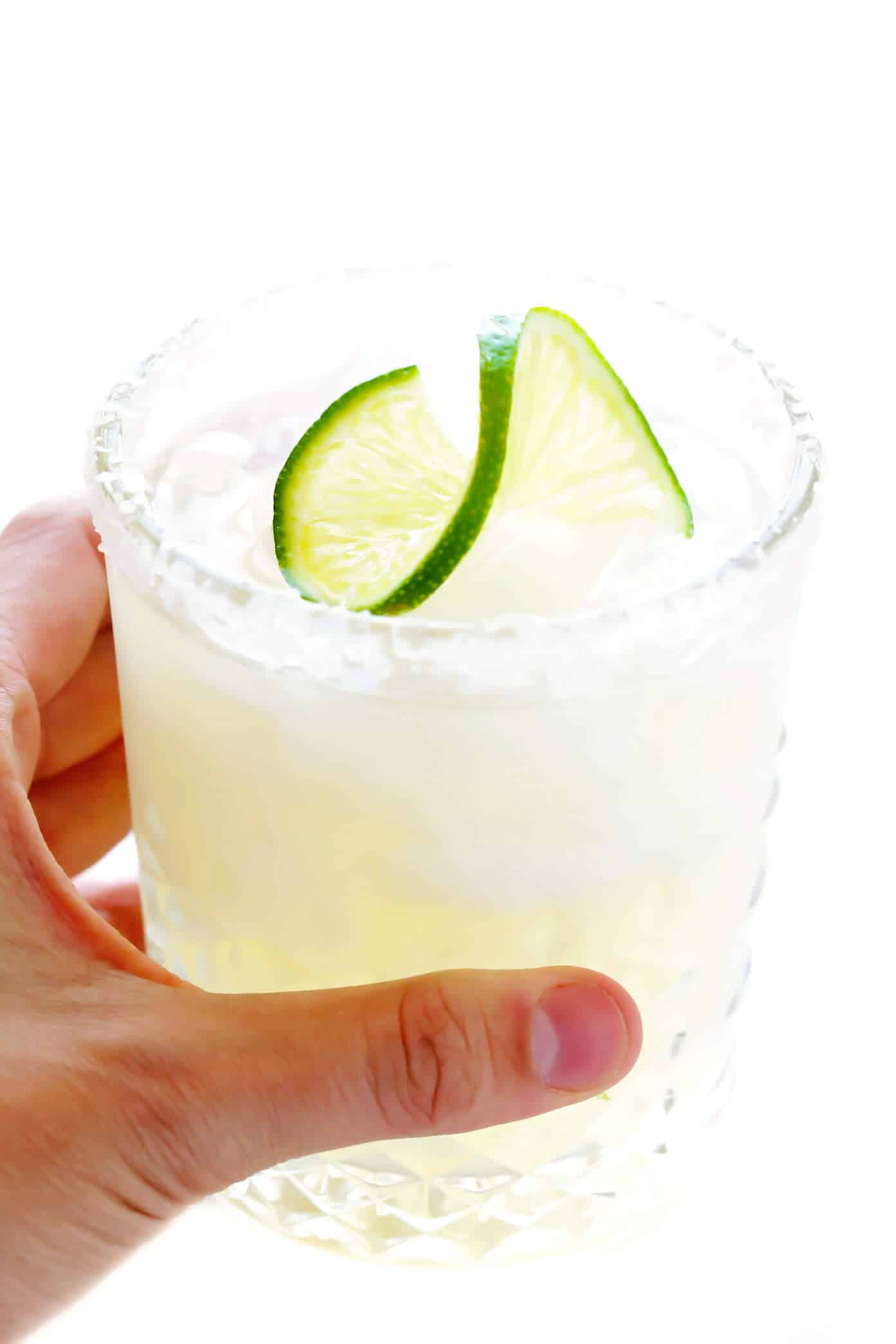 Learn how to make a margarita with this classic 3-ingredient margarita recipe! Instructions included for how to make a single-serving margarita cocktail or pitcher margaritas for a crowd. Plus options to make your drink smoky (with mezcal in place of tequila), spicy (with jalapeños or Tajín) or "skinny" (with fresh orange juice). | gimmesomeoven.com Classic Margarita Recipe in Glass with Lime