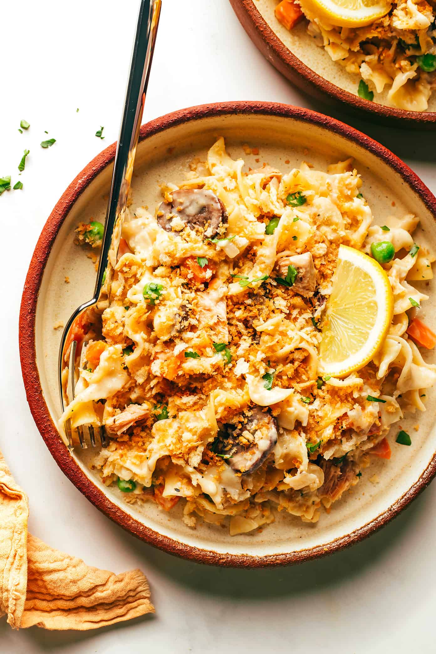This lightened-up tuna casserole recipe is tossed with a creamy cheddar garlic-herb sauce, lots of veggies, tender egg noodles and a crispy Panko topping. A simple and delicious weeknight dinner recipe that's ready to go in just 40 minutes. | gimmesomeoven.com Tuna Casserole on Plate with Lemon