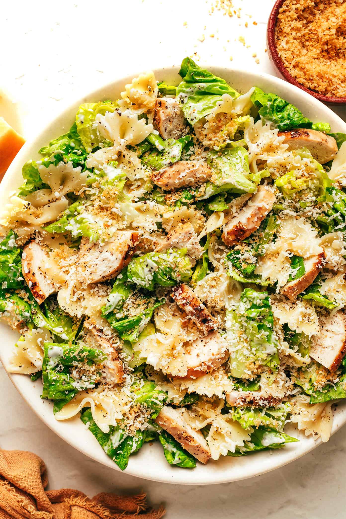 This Chicken Caesar Pasta Salad recipe is tossed with my favorite Caesar dressing, lots of Parmesan cheese, and the yummiest garlicky breadcrumbs. Feel free to use a different protein (such as salmon, shrimp, Italian sausage, bacon or roasted chickpeas) for the chicken if you prefer! | gimmesomeoven.com Chicken Caesar Pasta Salad with garlick breadcrumbs in bowl