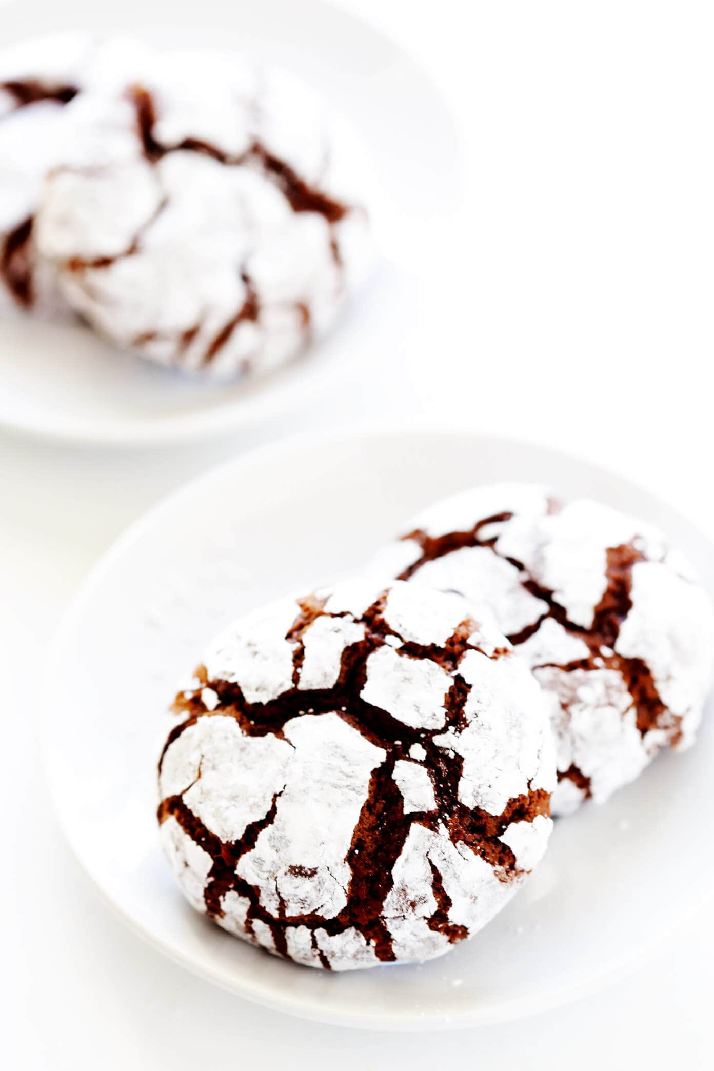 This chocolate crinkle cookies recipe (also known as snowballs) is easy to make and perfectly fudgy and dusted with powdered sugar. A classic dessert for Christmas and the holidays! | gimmesomeoven.com #chocolate #crinkle #cookies #dessert #christmas #holiday #baking Chocolate Crinkle Cookies on Plates