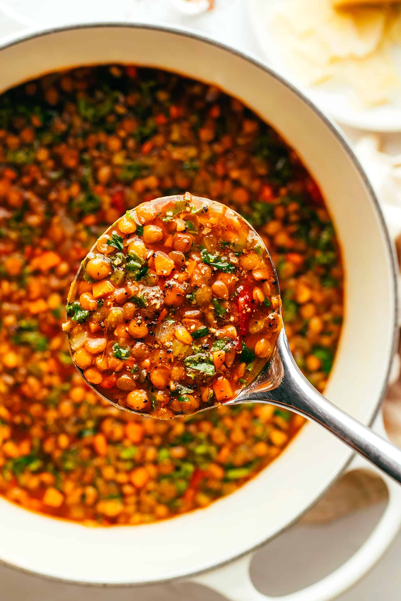 This Italian-inspired lentil soup recipe is made with a simple mix of veggies, lentils, greens and simmered in a tomato-herb broth and served with a garnish of basil and Parmesan. A simple vegetarian and gluten-free dinner recipe that's always so comforting and delicious! | gimmesomeoven.com Italian Lentil Soup in Stockpot with Ladle