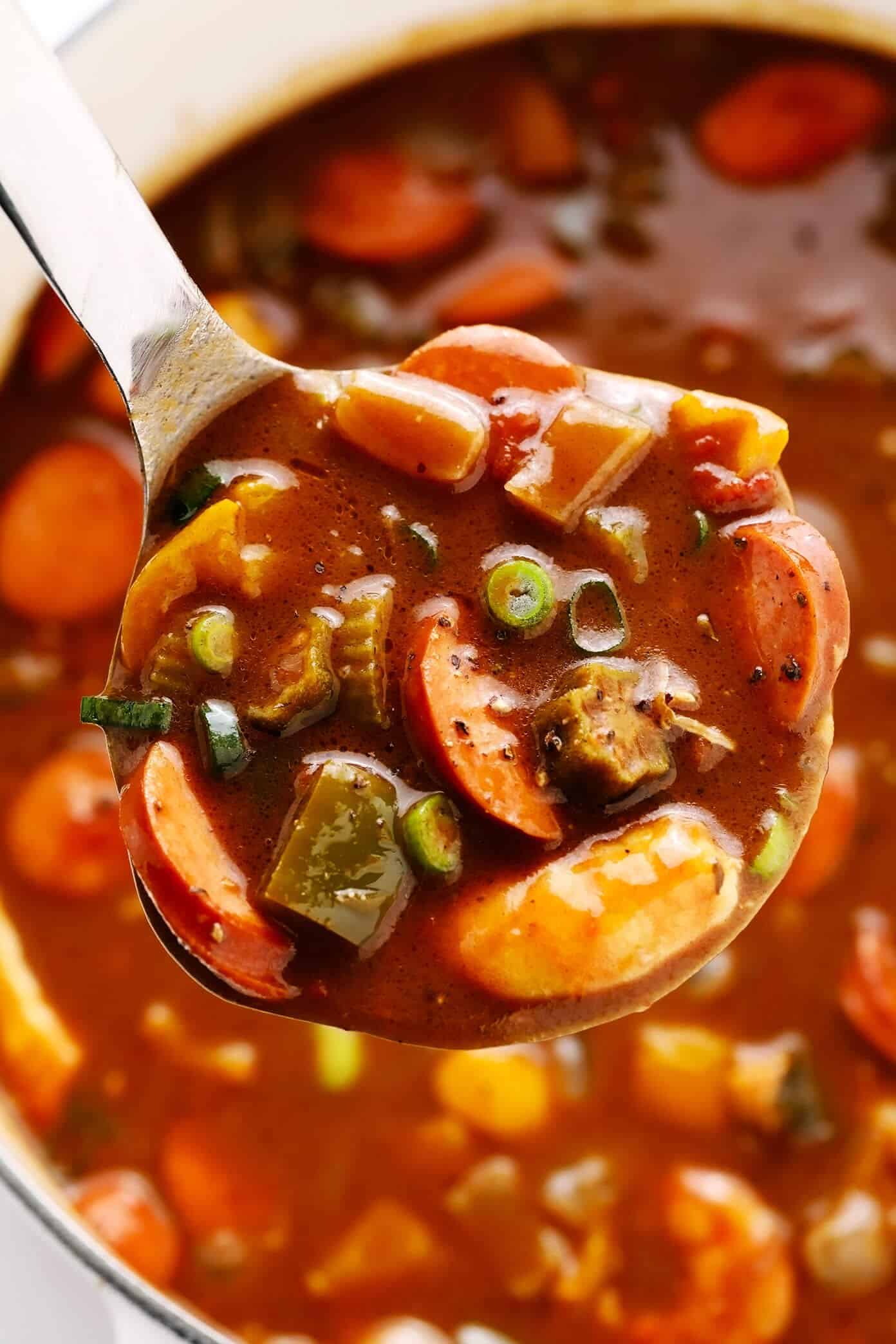 This Creole-style gumbo recipe is made with a richly-flavored dark roux, your choice of proteins (chicken, sausage and/or seafood), lots of veggies, and served over rice. So hearty, rich, and delicious! | gimmesomeoven.com #gumbo #soup #stew #creole #cajun #neworleans #mardigras #rice #dinner Ladle full of Sausage, Shrimp and Chicken Gumbo
