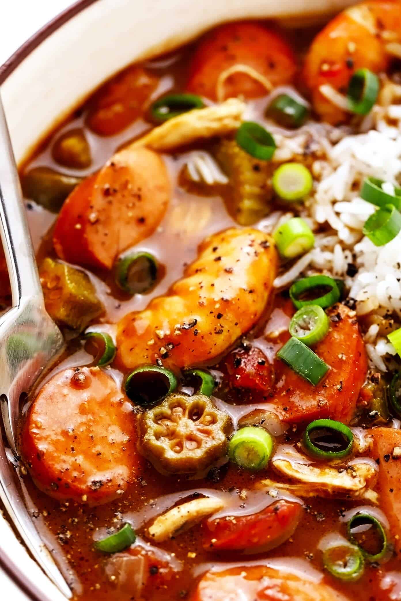 This Creole-style gumbo recipe is made with a richly-flavored dark roux, your choice of proteins (chicken, sausage and/or seafood), lots of veggies, and served over rice. So hearty, rich, and delicious! | gimmesomeoven.com #gumbo #soup #stew #creole #cajun #neworleans #mardigras #rice #dinner Closeup of Andouille Sausage, Shrimp and Chicken Gumbo with Rice
