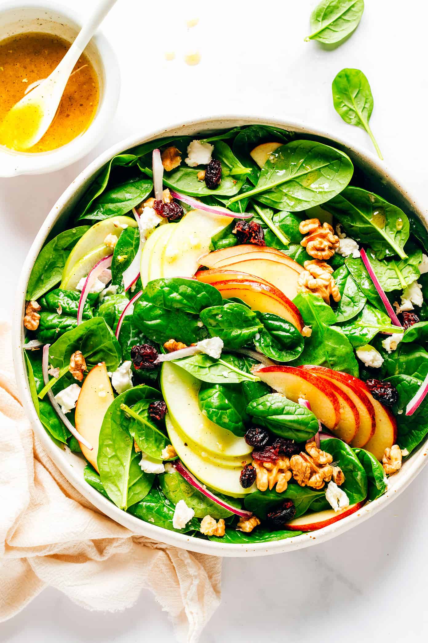 This classic apple spinach salad is tossed with your choice of nuts (walnuts, pecans, or almonds), cheese (blue, feta, goat, or cheddar), dried cranberries, red onions, and a simple vinaigrette. It's the perfect side salad on its own, or feel free to add some protein or avocado to make it an entree! | gimmesomeoven.com Apple Spinach Salad in Bowl with Apple Cider Vinaigrette