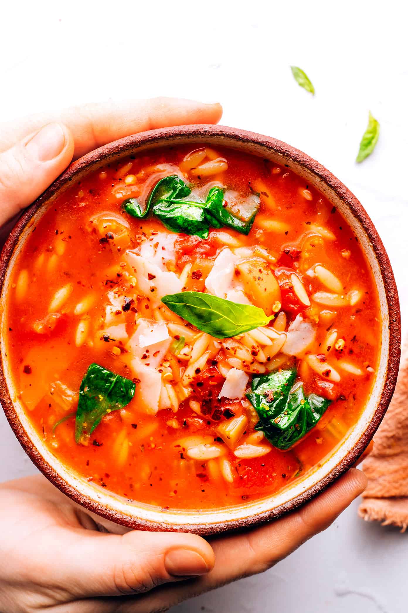 This Italian Orzo Spinach Soup is simmered with hearty pasta, veggies, greens in a zesty tomato-herb broth, then served warm with lots of Parmesan and fresh basil. It's one of our favorite vegetarian 30 minute meals, but feel free to add in sausage or chicken too if you'd like! | gimmesomeoven.com Bowl of Italian Orzo Spinach Soup
