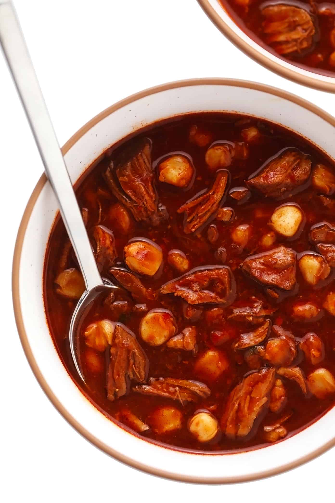 This traditional Mexican pozole recipe is made with tender pork and hominy and simmered in the most delicious chile broth, then piled high with your favorite fresh toppings. Crock-Pot and Instant Pot options for this soup are included too! | gimmesomeoven.com Serving bowl of red pozole without toppings
