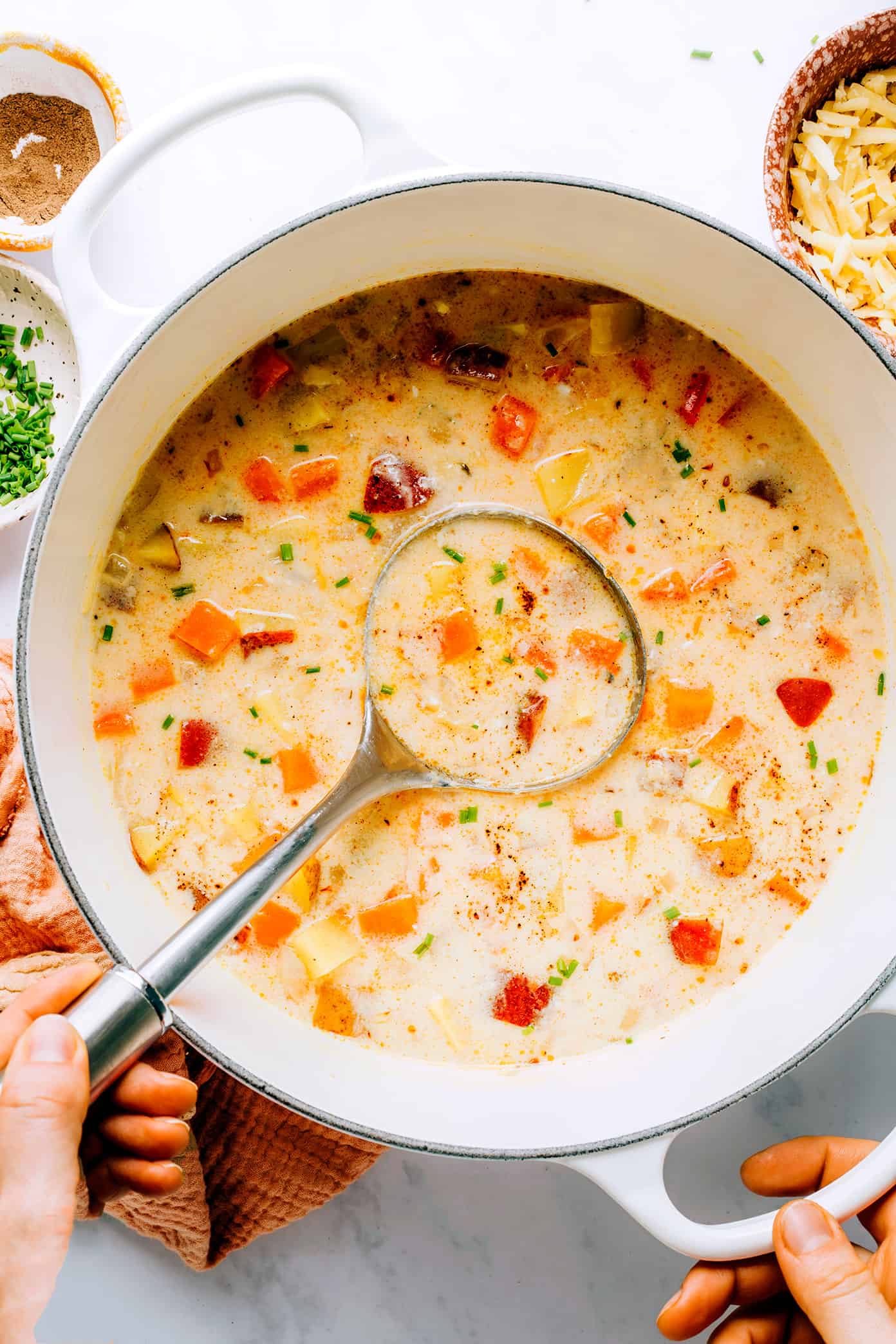 This Three Potato Soup is made with a zesty, creamy cheddar broth and a sweet and savory combination of Yukon gold potatoes, red potatoes, and sweet potatoes. Easy to make in about 30 minutes and always so delicious and comforting! Feel free to leave the soup vegetarian, or add in some bacon, ham, sausage or chicken if you prefer. (Gluten-free and vegan options included too.) | gimmesomeoven.com Dutch oven with three potato soup and ladle