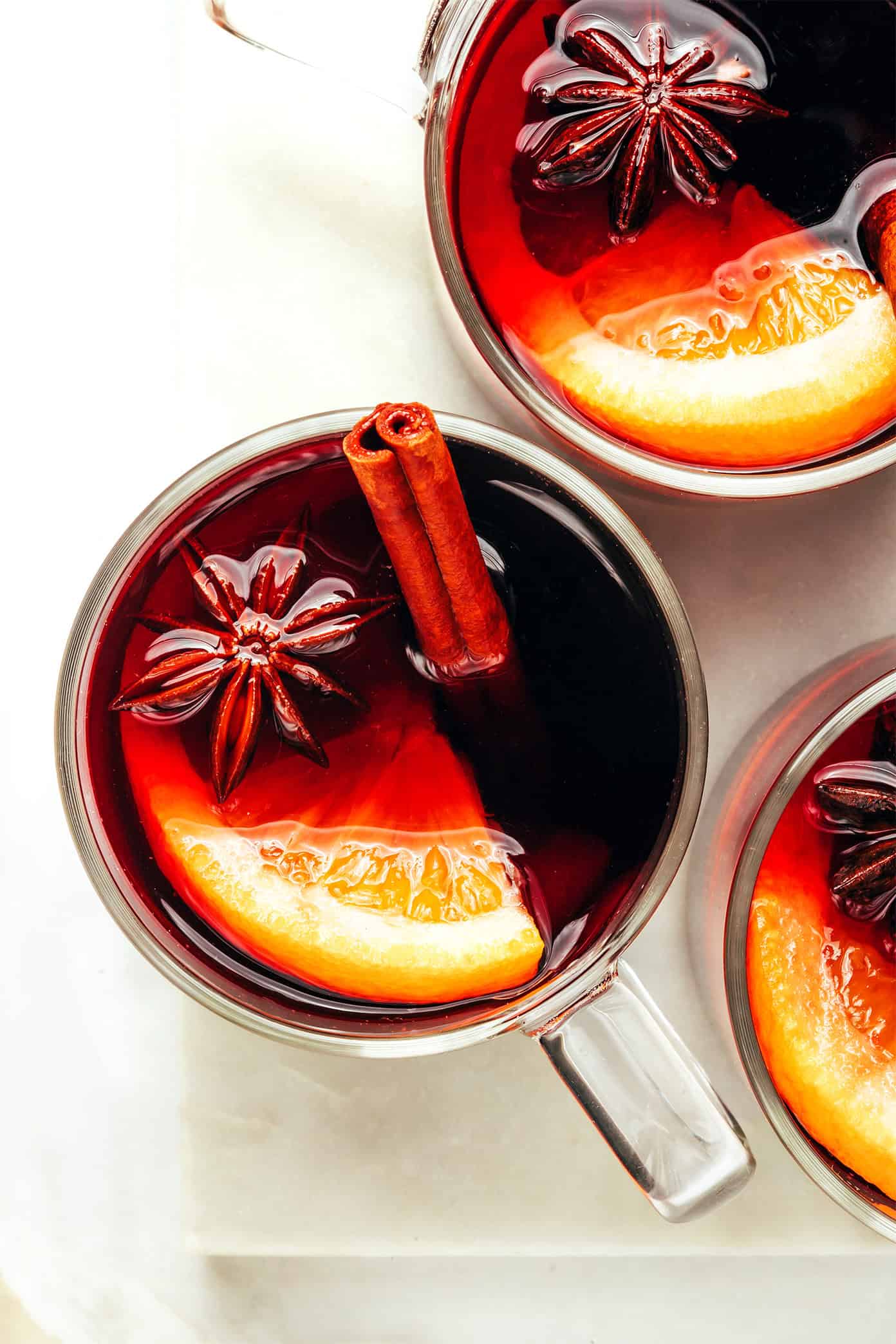This delicious mulled wine recipe is ready to go in 20 minutes and couldn't be easier to make. Just warm a full-bodied red with brandy (or orange liqueur) and your favorite aromatics (orange, cinnamon, star anise, etc). Then the most delicious hot wine will be yours to enjoy in no time! The perfect easy drink for holiday entertaining. | gimmesomeoven.com Mulled Wine in Mugs