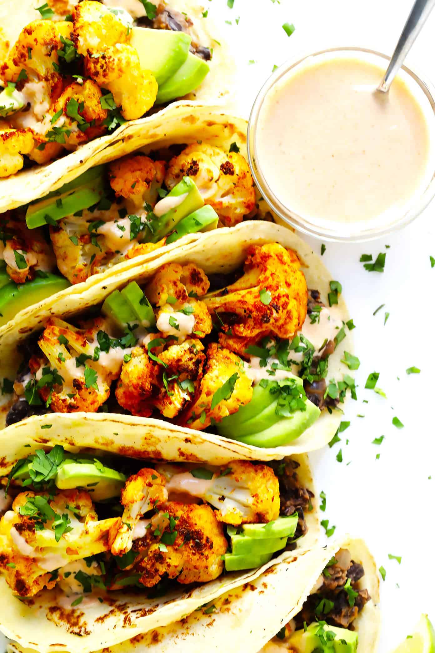 These Roasted Cauliflower and Black Bean Tacos are naturally vegetarian, vegan and gluten-free, they're topped with avocado, cilantro, and a zesty cumin lime crema, and they are SO delicious! | Gimme Some Oven #cauliflower #tacos #healthy #dinner #recipe #vegetarian #glutenfree Roasted Cauliflower and Black Bean Tacos with Crema