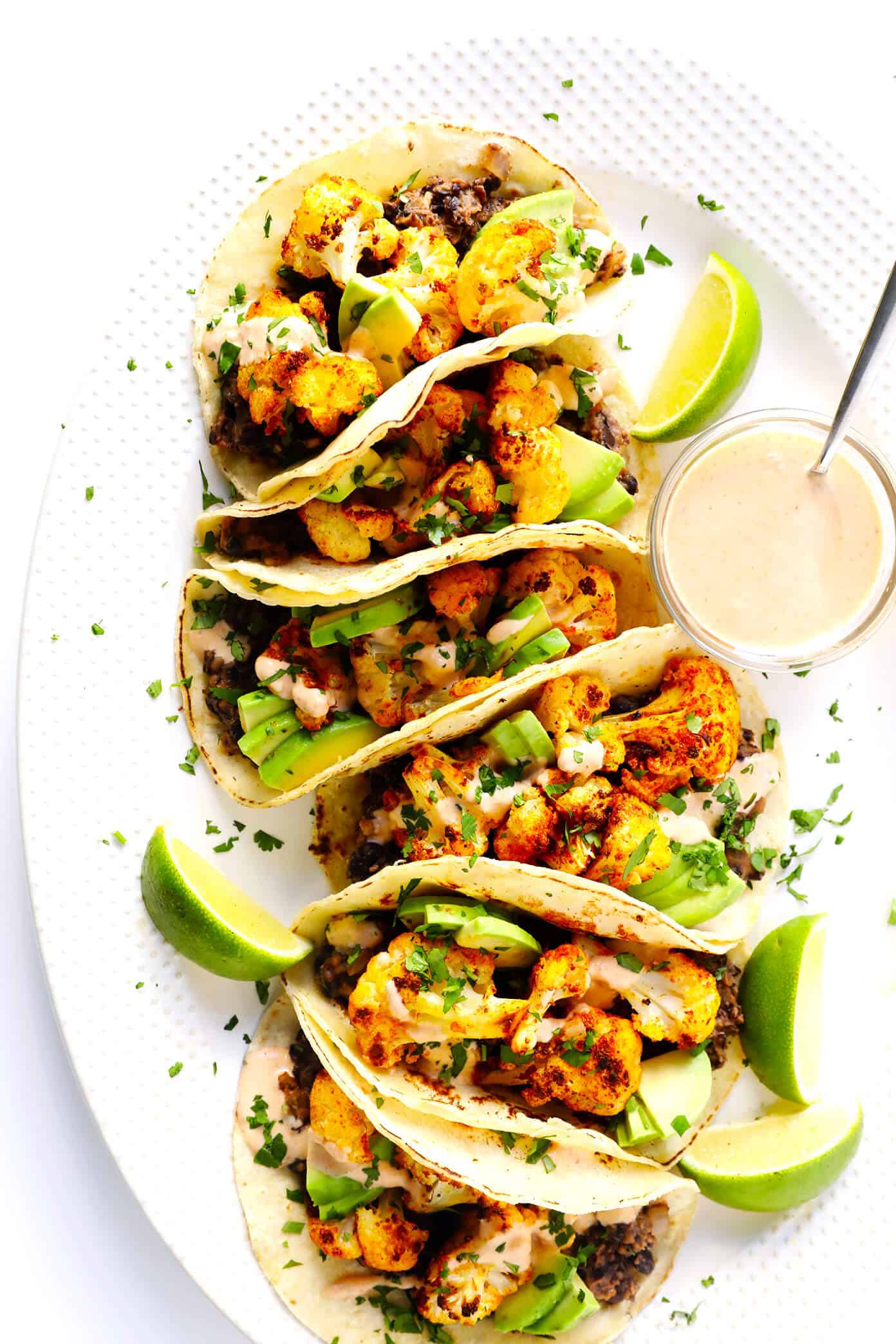 These Roasted Cauliflower and Black Bean Tacos are naturally vegetarian, vegan and gluten-free, they're topped with avocado, cilantro, and a zesty cumin lime crema, and they are SO delicious! | Gimme Some Oven #cauliflower #tacos #healthy #dinner #recipe #vegetarian #glutenfree #vegan Roasted Cauliflower and Black Bean Tacos Recipe