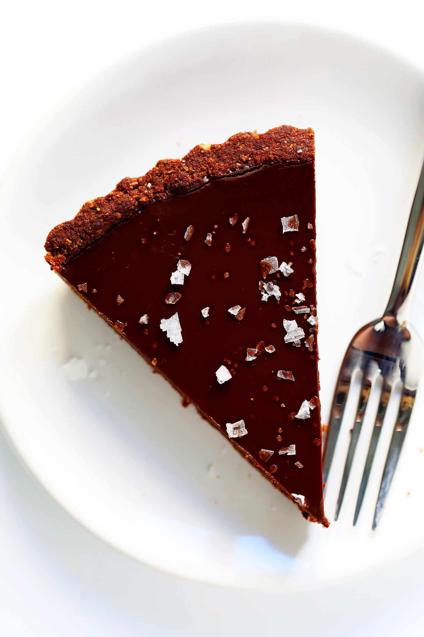 LOVE this Salted Dark Chocolate Tart recipe! It's quick and easy to make ahead, made with a gluten-free almond crust and zero heavy cream, and it's SO decadent and delicious. The perfect dessert for Valentine's Day or anytime you're craving some chocolate. | Gimme Some Oven #chocolate #tart #darkchocolate #dessert #sweets #valentines #glutenfree #vegan #vegetarian Vegan Chocolate Tart Dessert