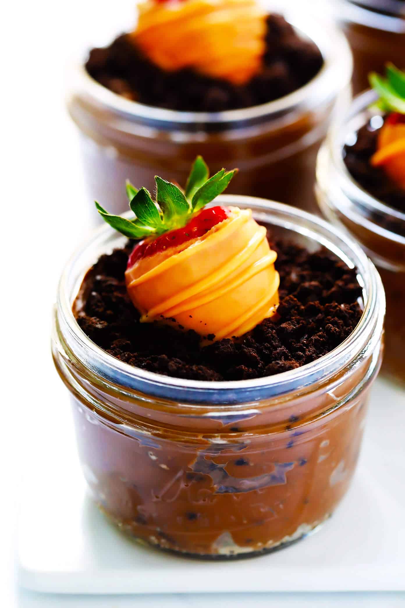 Love these Carrot Patch "Dirt" Cups! They're made with a chocolate avocado mousse pudding "dirt cake", chocolate-covered strawberry "carrots", and a sprinkling of Oreos, and they are SO delicious and fun! The perfect Spring (or Easter!) dessert that kids and adults will love alike. | Gimme Some Oven #dirtcake #easter #spring #chocolate #dessert #treats Carrot Patch Dirt Cups with Chocolate-Covered Strawberries
