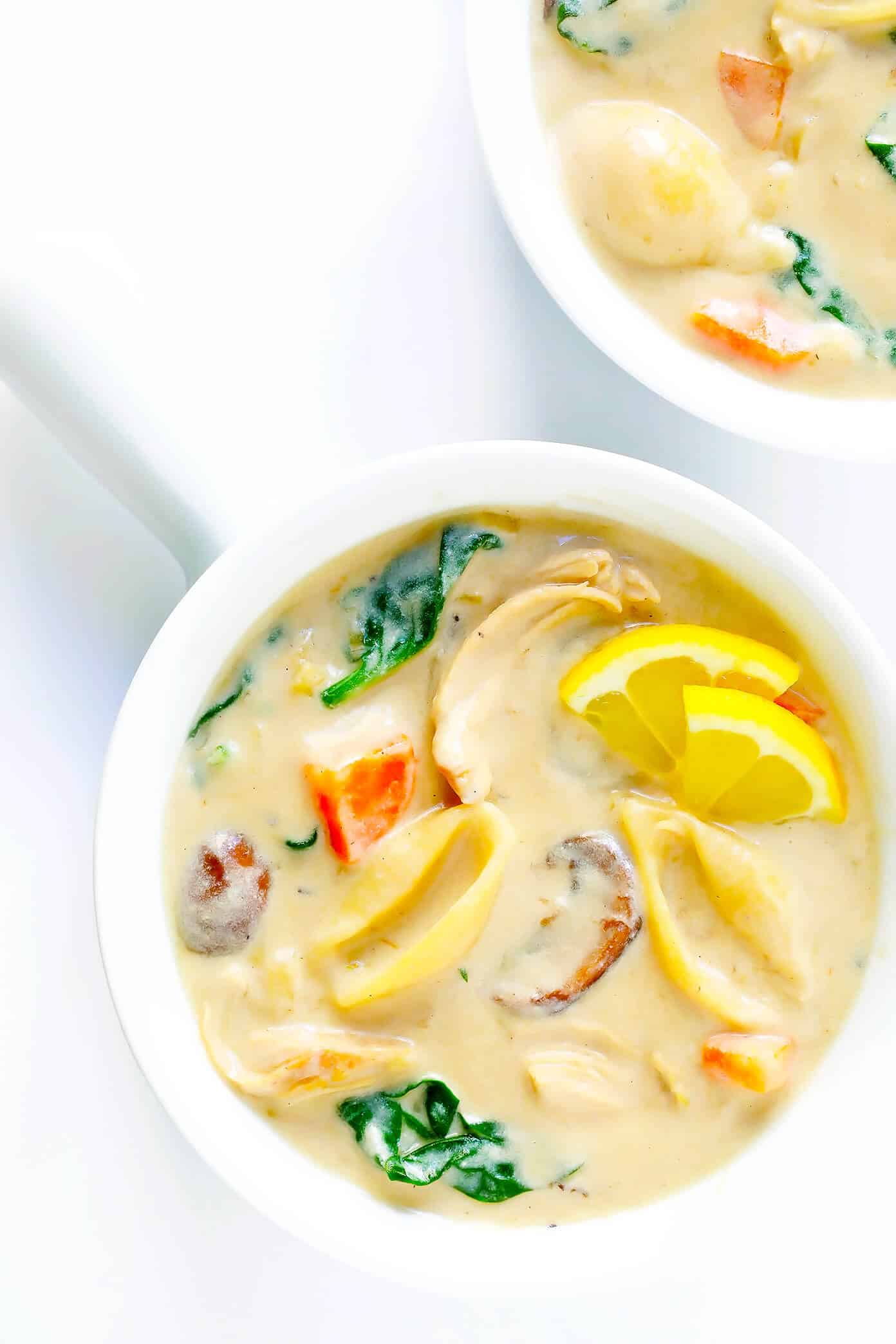 This Creamy Chicken Marsala Soup recipe is the BEST. It's made with pasta, mushrooms, carrots, and spinach...all simmered together in the most delicious creamy, garlicky, wine-infused broth. Top with Parmesan and lemon for a delicious, comforting dinner. | Gimme Some Oven #chickenmarsala #chickensoup #souprecipes #dinnerrecipes #comfortfood Creamy Chicken Marsala Soup in bowls