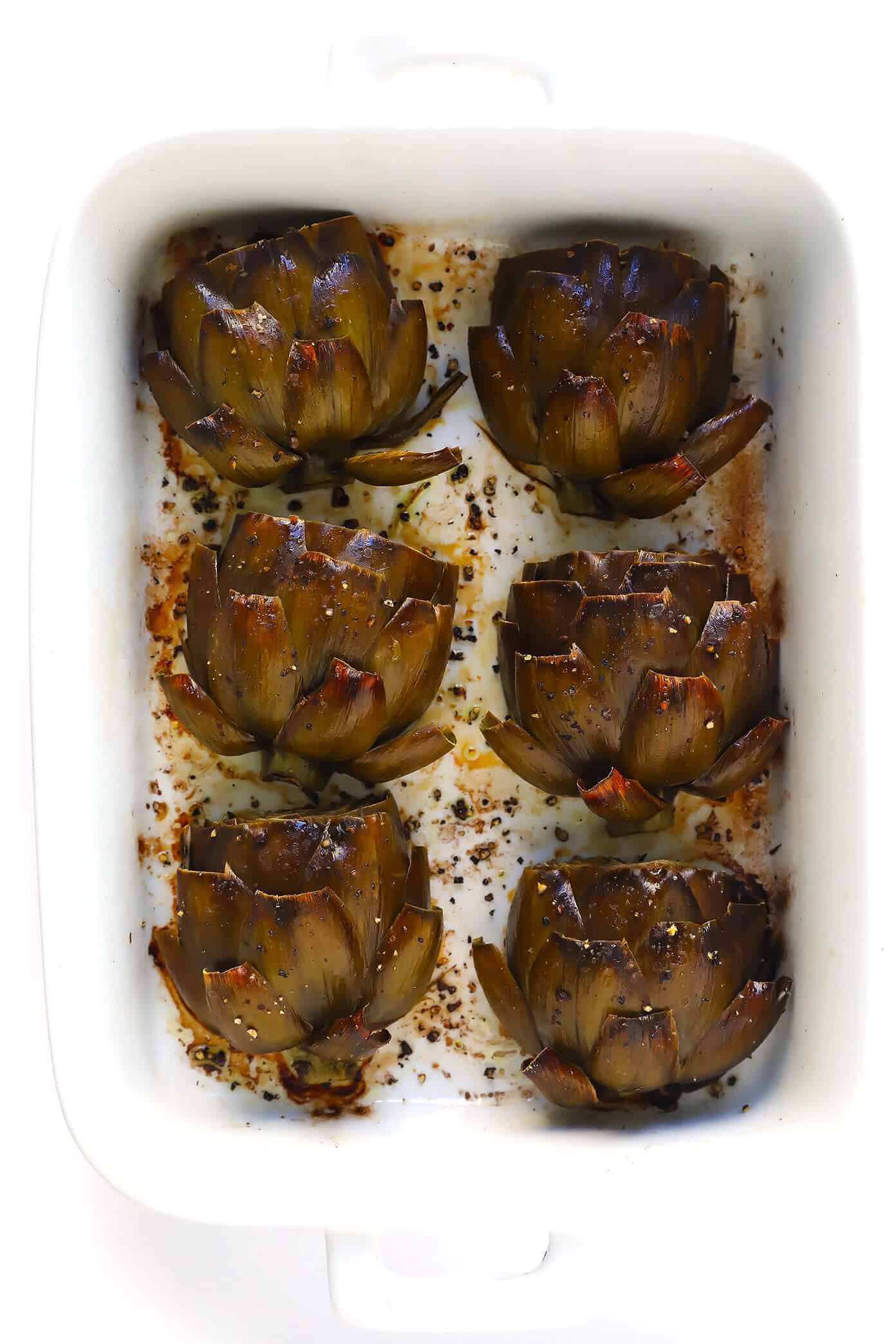Seriously the most amazing roasted artichokes recipe! They're stuffed with lots of garlic and herbs, seasoned with lots of lemon and black pepper, and roasted to crispy, tender perfection. The perfect vegetable side dish! | Gimme Some Oven #artichokes #roasted #sidedish #vegetable #glutenfree #vegan The Most Amazing Oven Roasted Artichokes