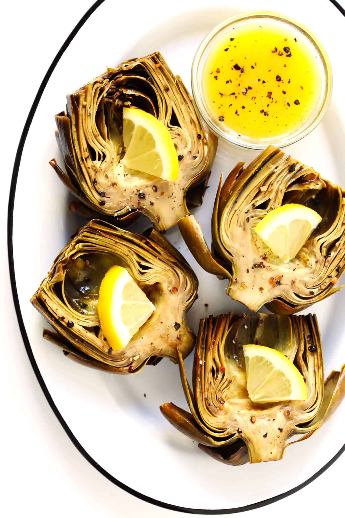 Seriously the most amazing roasted artichokes recipe! They're stuffed with lots of garlic and herbs, seasoned with lots of lemon and black pepper, and roasted to crispy, tender perfection. The perfect vegetable side dish! | Gimme Some Oven #artichokes #roasted #sidedish #vegetable #glutenfree #vegan Oven Roasted Artichokes with Lemon Butter Sauce