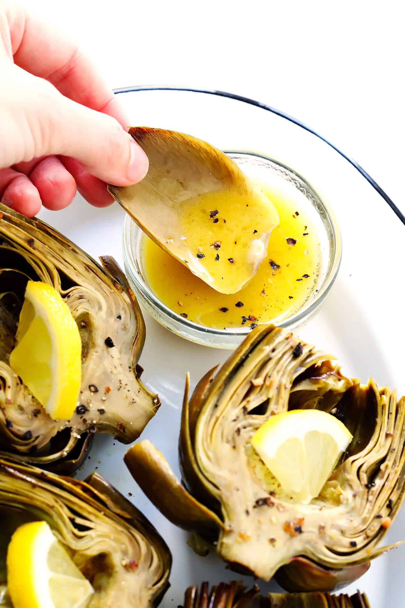Seriously the most amazing roasted artichokes recipe! They're stuffed with lots of garlic and herbs, seasoned with lots of lemon and black pepper, and roasted to crispy, tender perfection. The perfect vegetable side dish! | Gimme Some Oven #artichokes #roasted #sidedish #vegetable #glutenfree #vegan Oven Roasted Artichokes with Lemon Butter Dipping Sauce