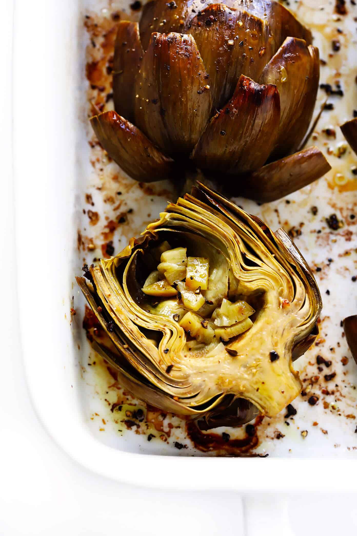 Seriously the most amazing roasted artichokes recipe! They're stuffed with lots of garlic and herbs, seasoned with lots of lemon and black pepper, and roasted to crispy, tender perfection. The perfect vegetable side dish! | Gimme Some Oven #artichokes #roasted #sidedish #vegetable #glutenfree #vegan How To Eat Roasted Artichokes (with Roasted Garlic)