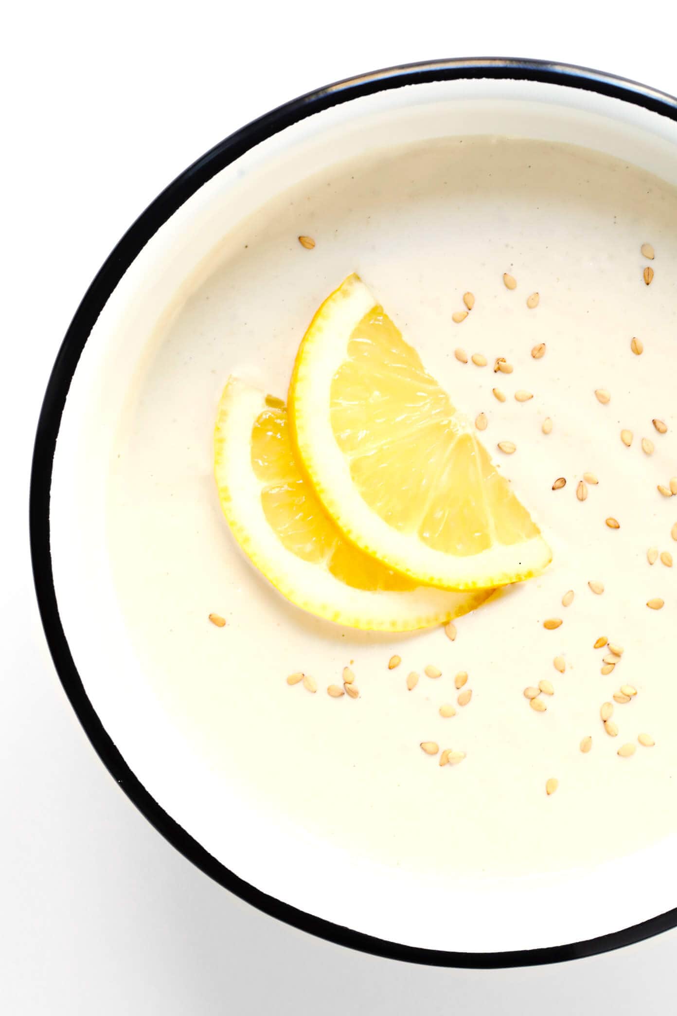 This 5-Minute Dreamy Tahini Dip recipe is quick and easy to make in the blender, it's naturally gluten-free and vegan, and it goes with just about everything. The perfect healthy appetizer or snack! | Gimme Some Oven #tahini #dip #appetizer #vegan #glutenfree Blender Tahini Dip in a bowl sprinkled with sesame and lemon