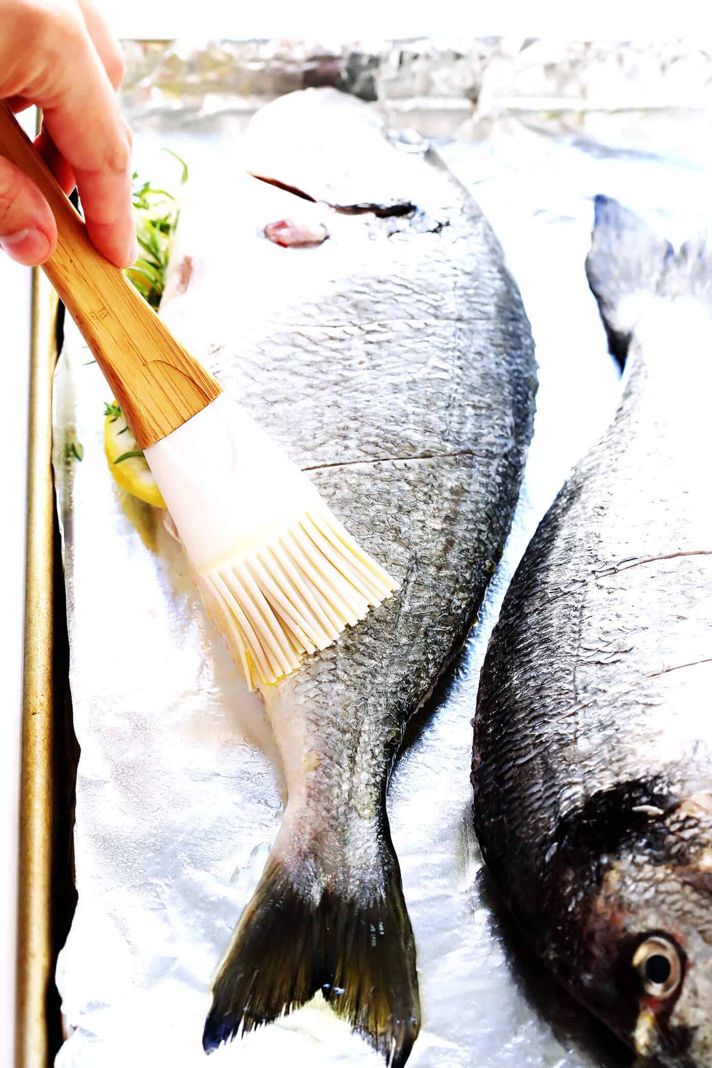 Learn how to cook a whole fish in the oven with this easy step-by-step tutorial and recipe! It's easy to make with mahi mahi, sea bass, branzino, red snapper, or whatever your favorite fish may be, and seasoned with a simple blend of lemon, garlic and herbs. The perfect healthy dinner! | Gimme Some Oven #fish #dinner #healthy #recipe #mahimahi #seabass How To Make Baked Fish In The Oven