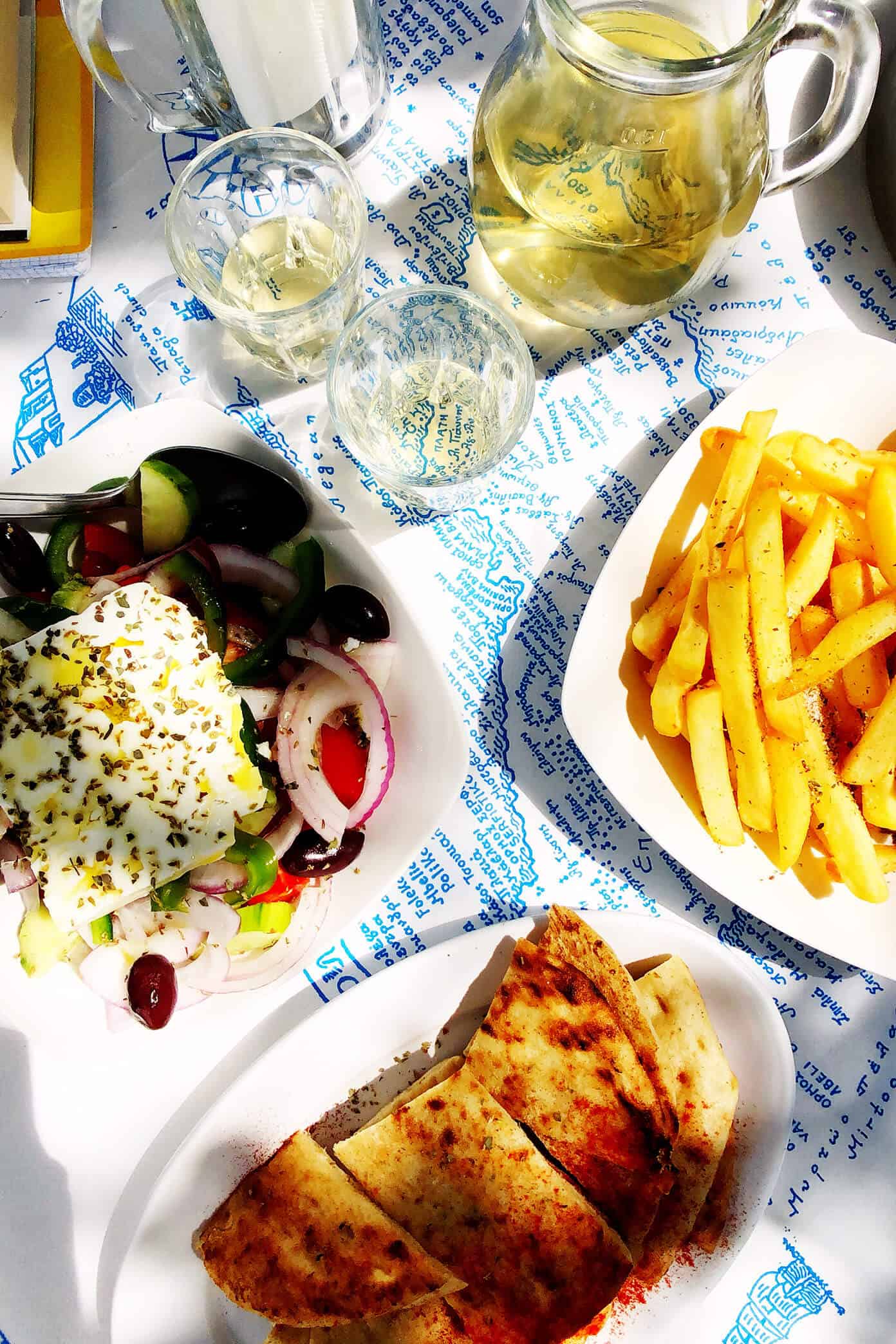 The Gimme Some Oven travel guide for restaurants to eat, hotels to stay and places to visit in Santorini, Greece. | Gimme Some Oven #santorini #greece #travel #traveltips #europe #vacation #islands #hotel #restaurant Greek Salad, Pita, Fries and Wine at Souvlaki Club Restaurant in Folegandros, Greece