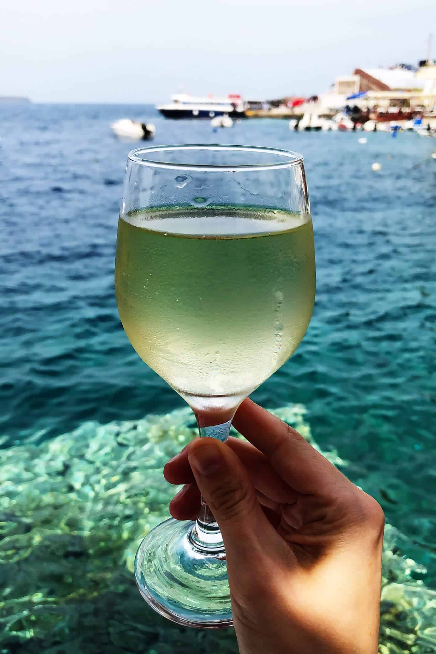 The Gimme Some Oven travel guide for restaurants to eat, hotels to stay and places to visit in Santorini, Greece. | Gimme Some Oven #santorini #greece #travel #traveltips #europe #vacation #islands #hotel #restaurant White Wine at Sunset Tavern in Santorini, Greece