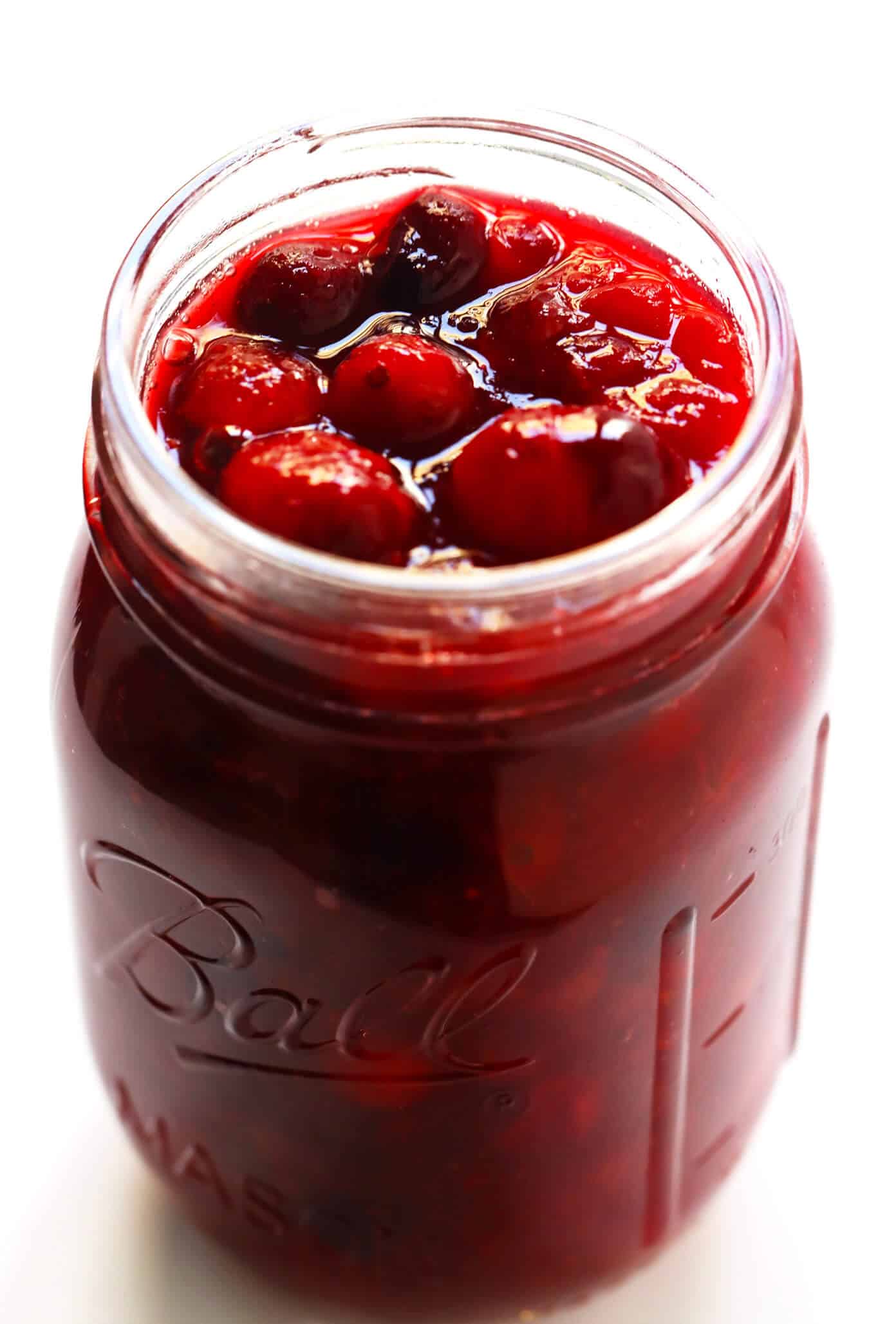 This homemade Maple Cranberry Sauce recipe is naturally-sweetened with real maple syrup, it's easy to make in about 15 minutes, and it's totally delicious. Perfect for Thanksgiving, Christmas, or anytime you'd love an extra pop of color on the dinner table. | Gimme Some Oven #cranberry #sauce #thanksgiving #naturallysweetened #sugarfree #maple #vegan #glutenfree #vegetarian #side #christmas #holiday #dinner Maple Cranberry Sauce in Canning Jar