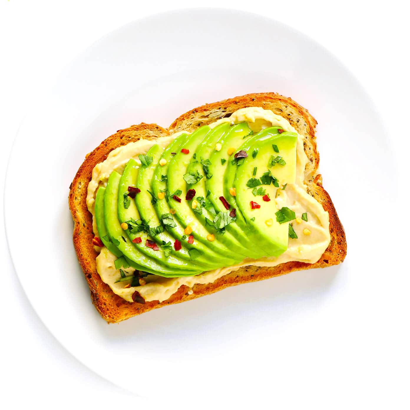 Hummus Toast is fun to customize with your favorite toppings, and makes for a delicious easy breakfast, lunch, dinner or healthy snack! Read more for details on 8 of our favorite toppings -- "everything", avocado, elote, tomato basil, lox, fried egg, mediterranean or honey banana. | gimmesomeoven.com #hummus #toast #healthy #breakfast #dinner #lunch #snack Avocado Hummus Toast