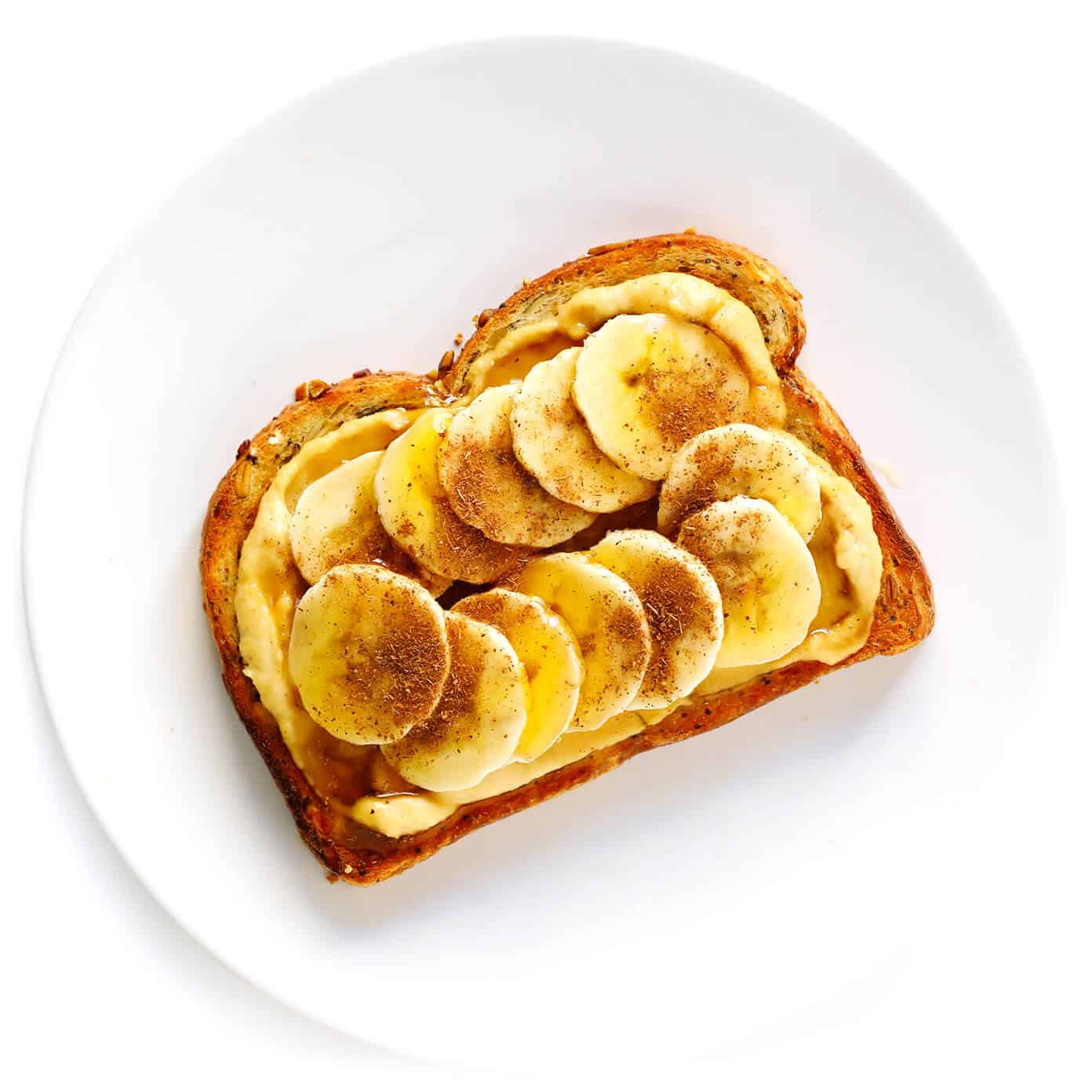 Hummus Toast is fun to customize with your favorite toppings, and makes for a delicious easy breakfast, lunch, dinner or healthy snack! Read more for details on 8 of our favorite toppings -- "everything", avocado, elote, tomato basil, lox, fried egg, mediterranean or honey banana. | gimmesomeoven.com #hummus #toast #healthy #breakfast #dinner #lunch #snack Banana Hummus Toast