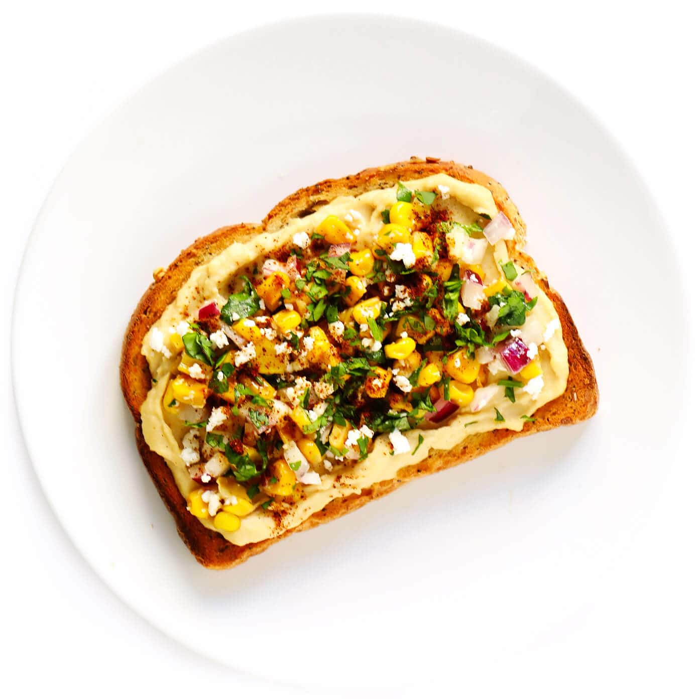 Hummus Toast is fun to customize with your favorite toppings, and makes for a delicious easy breakfast, lunch, dinner or healthy snack! Read more for details on 8 of our favorite toppings -- "everything", avocado, elote, tomato basil, lox, fried egg, mediterranean or honey banana. | gimmesomeoven.com #hummus #toast #healthy #breakfast #dinner #lunch #snack Elote (Mexican Street Corn) Hummus Toast