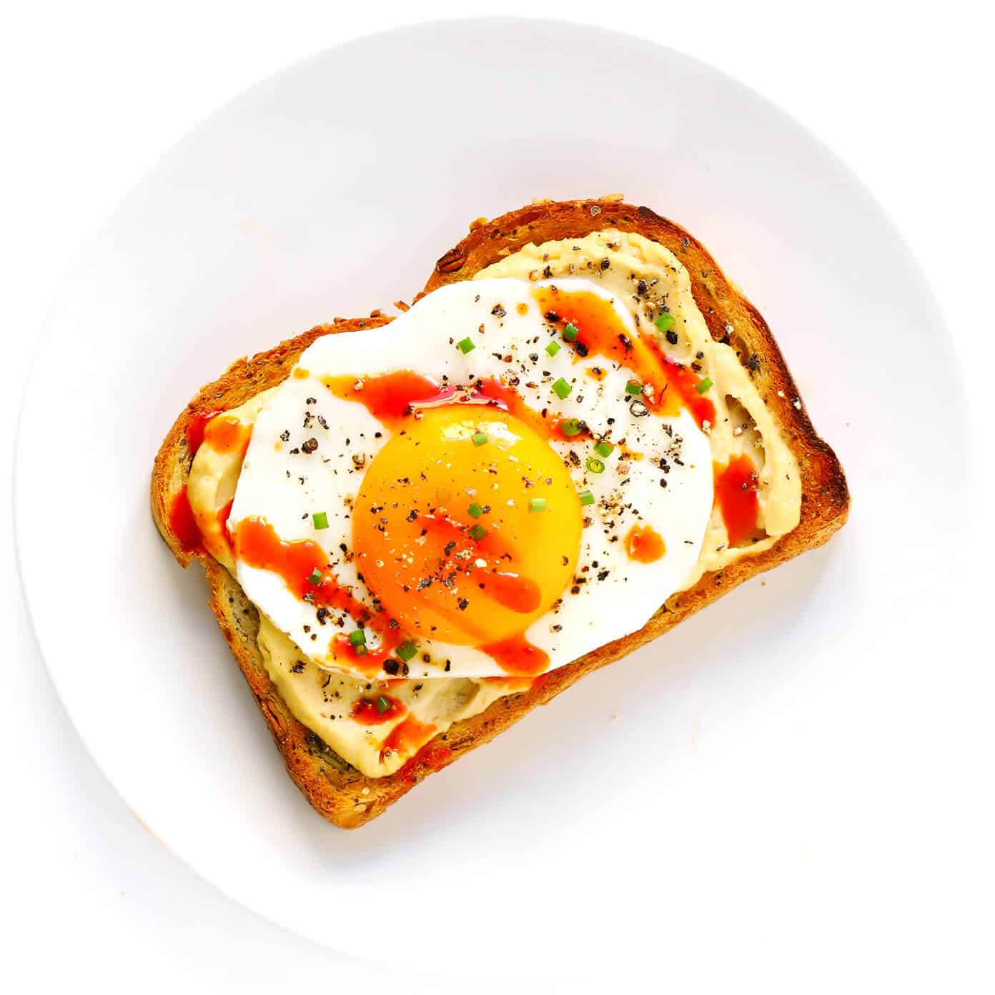 Hummus Toast is fun to customize with your favorite toppings, and makes for a delicious easy breakfast, lunch, dinner or healthy snack! Read more for details on 8 of our favorite toppings -- "everything", avocado, elote, tomato basil, lox, fried egg, mediterranean or honey banana. | gimmesomeoven.com #hummus #toast #healthy #breakfast #dinner #lunch #snack Fried Egg Hummus Toast