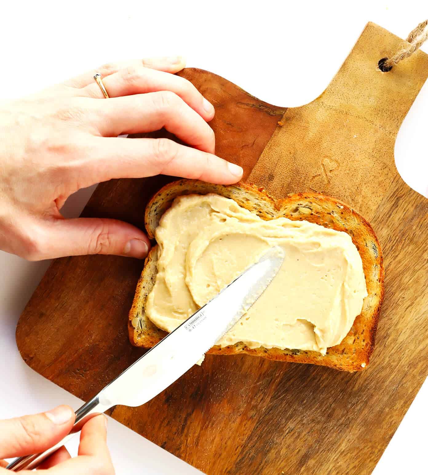 Hummus Toast is fun to customize with your favorite toppings, and makes for a delicious easy breakfast, lunch, dinner or healthy snack! Read more for details on 8 of our favorite toppings -- "everything", avocado, elote, tomato basil, lox, fried egg, mediterranean or honey banana. | gimmesomeoven.com #hummus #toast #healthy #breakfast #dinner #lunch #snack How To Make Hummus Toast