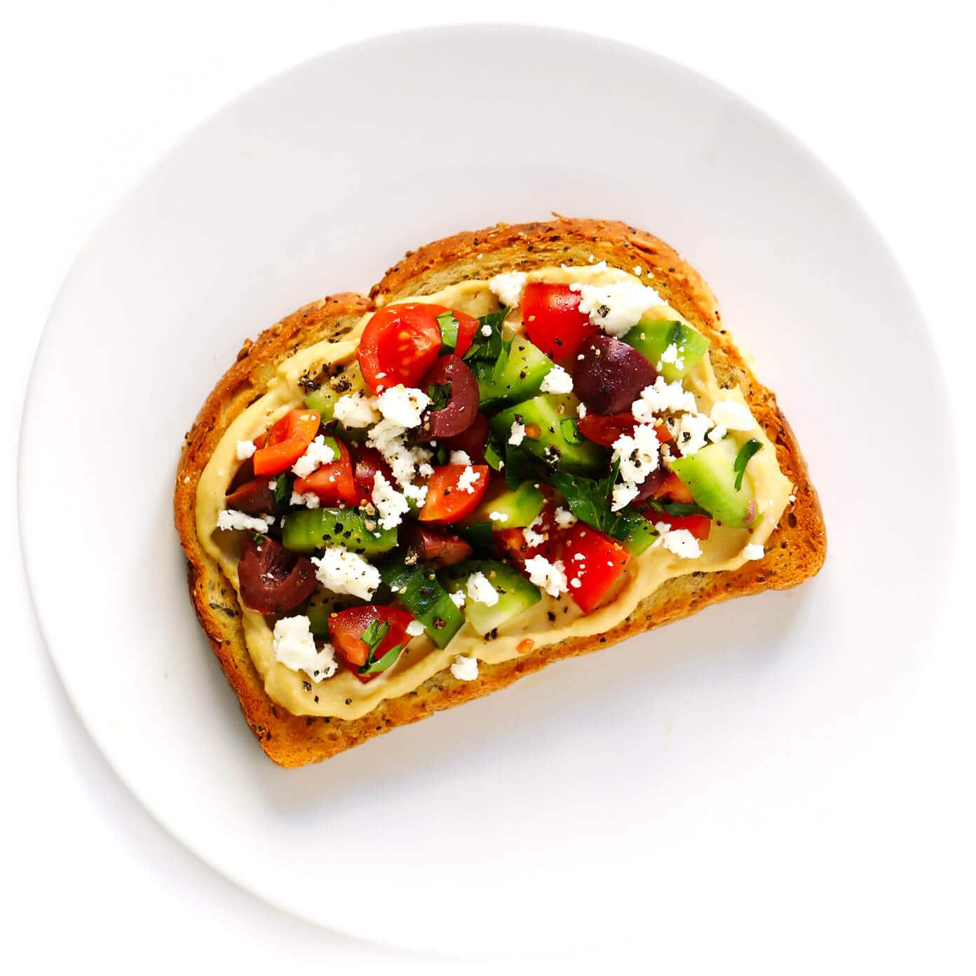 Hummus Toast is fun to customize with your favorite toppings, and makes for a delicious easy breakfast, lunch, dinner or healthy snack! Read more for details on 8 of our favorite toppings -- "everything", avocado, elote, tomato basil, lox, fried egg, mediterranean or honey banana. | gimmesomeoven.com #hummus #toast #healthy #breakfast #dinner #lunch #snack Mediterranean Hummus Toast