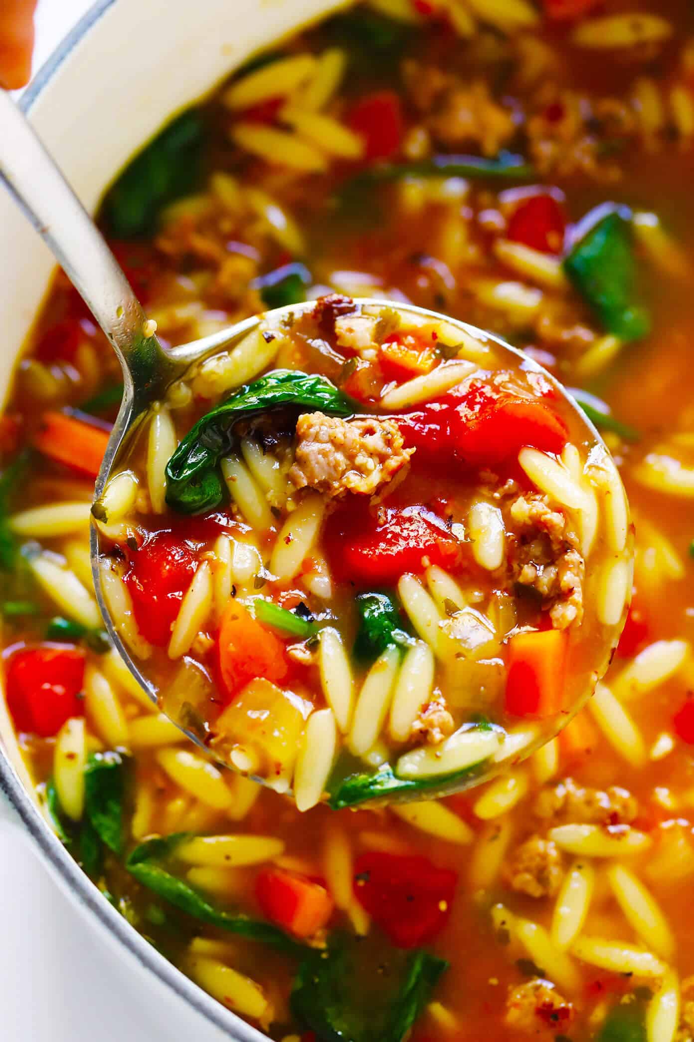This Italian Sausage and Orzo Soup recipe is easy to make with your choice of veggies, it's seasoned with a zesty garlic tomato broth, and tastes SO cozy and comforting. The perfect easy dinner recipe that also makes great leftovers for later! | gimmesomeoven.com #italian #soup #pasta #orzo #sausage #dinner #freezermeal #mealprep #healthy Italian Sausage Soup with Orzo and Spinach