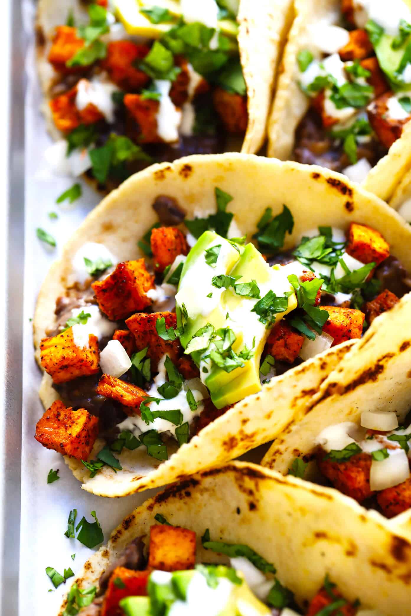 These zesty roasted sweet potato tacos are made with refried black beans, fresh avocado, lime crema, and your choice of toppings. Easy to make, naturally vegan and gluten-free, and SO delicious! | gimmesomeoven.com #tacos #sweetpotato #vegetarian #vegan #glutenfree #healthy #mexican #dinner #beans Roasted Sweet Potato and Black Bean Tacos Recipe