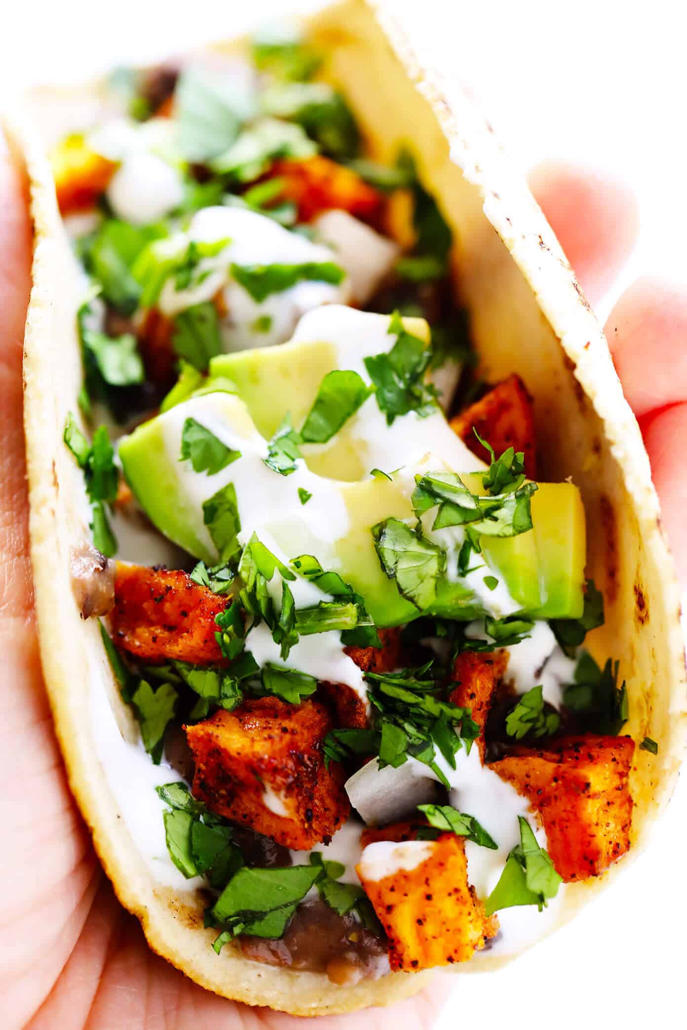 These zesty roasted sweet potato tacos are made with refried black beans, fresh avocado, lime crema, and your choice of toppings. Easy to make, naturally vegan and gluten-free, and SO delicious! | gimmesomeoven.com #tacos #sweetpotato #vegetarian #vegan #glutenfree #healthy #mexican #dinner #beans Sweet Potato Tacos with Refried Beans, Avocado and Lime Crema
