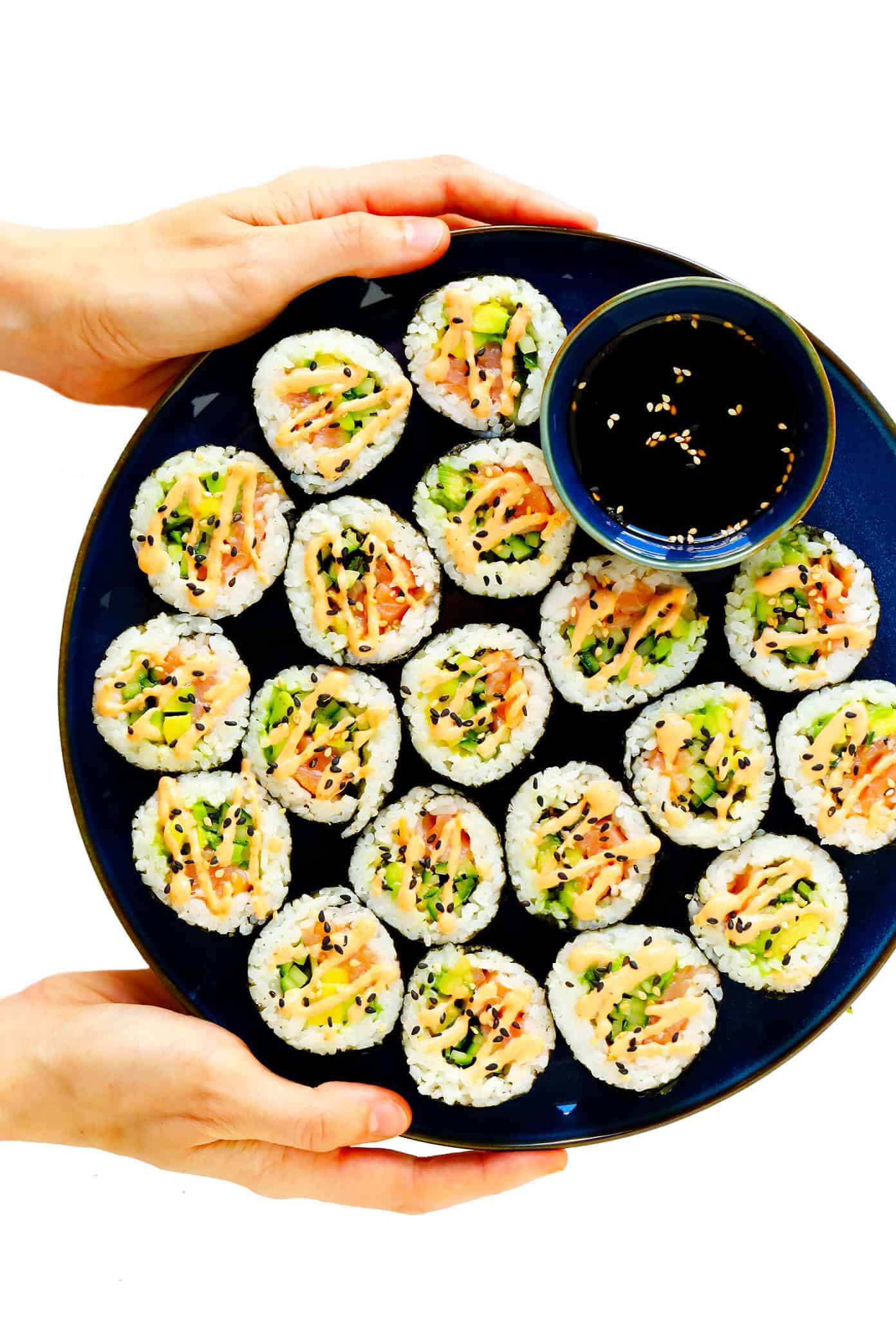 Learn how to make sushi rolls with this easy maki rolls recipe! They are surprisingly easy to make, and 100% customizable with whatever ingredients you love best. Spicy sriracha sauce recipe included if you would like to make spicy tuna, salmon or veggie rolls! | gimmesomeoven.com #sushi #rolls #maki #japanese #howto #salmon #vegetarian #vegan #healthy #dinner #entertaining Plate of Spicy Salmon Avocado Sushi Rolls with Soy Sauce