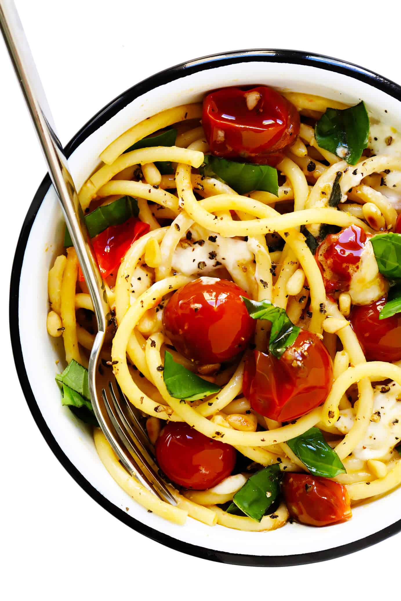 This garlicky pasta with burst cherry tomatoes, burrata cheese and fresh basil is easy to make in less than 30 minutes and outrageously delicious! Feel free to add in some chicken or shrimp or extra veggies too, if you would like. | gimmesomeoven.com #pasta #burrata #cheese #mozzarella #italian #tomato #sauce #basil #dinner #easy Serving bowl of pasta with cherry tomatoes, burrata and basil