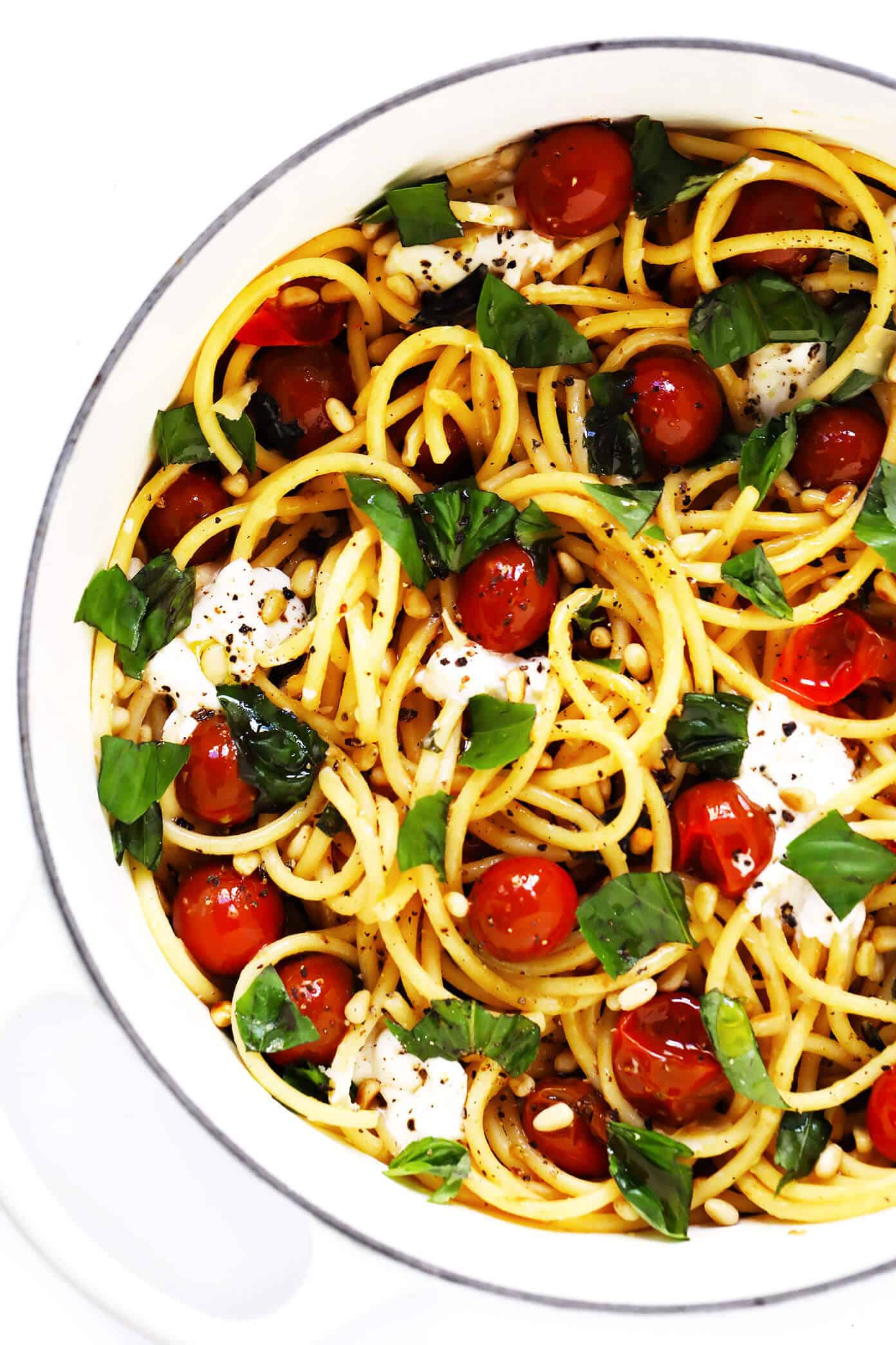 This garlicky pasta with burst cherry tomatoes, burrata cheese and fresh basil is easy to make in less than 30 minutes and outrageously delicious! Feel free to add in some chicken or shrimp or extra veggies too, if you would like. | gimmesomeoven.com #pasta #burrata #cheese #mozzarella #italian #tomato #sauce #basil #dinner #easy Pot of bucatini pasta with burrata cheese, cherry tomatoes, basil and pine nuts