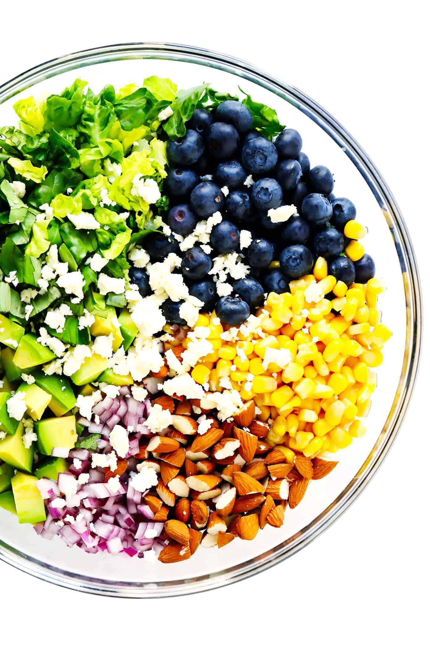This Blueberry, Corn & Avocado Chopped Salad recipe is tossed with lots of fresh basil, toasted almonds, crumbled feta, red onions, and an easy lemon dressing. The perfect salad for summertime! | gimmesomeoven.com #salad #blueberry #corn #avocado #chopped #glutenfree #healthy #dinner #vegetarian #summer Bowl of ingredients to make blueberry corn and avocado chopped salad