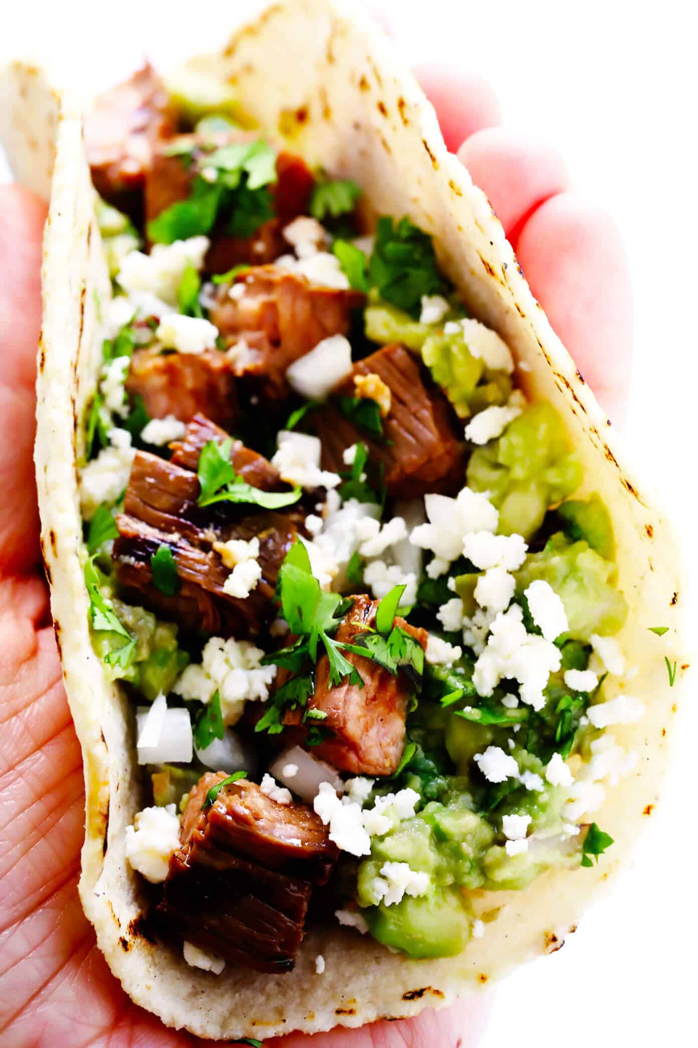My favorite recipe for street-style Mexican carne asada tacos -- made with tender marinated grilled steak, soft corn tortillas, guacamole or sliced avocado, and whatever other toppings sound good! | gimmesomeoven.com #carneasada #beef #steak #tacos #mexican #avocado #guacamole #glutenfree #dinner Carne Asada Taco Closeup