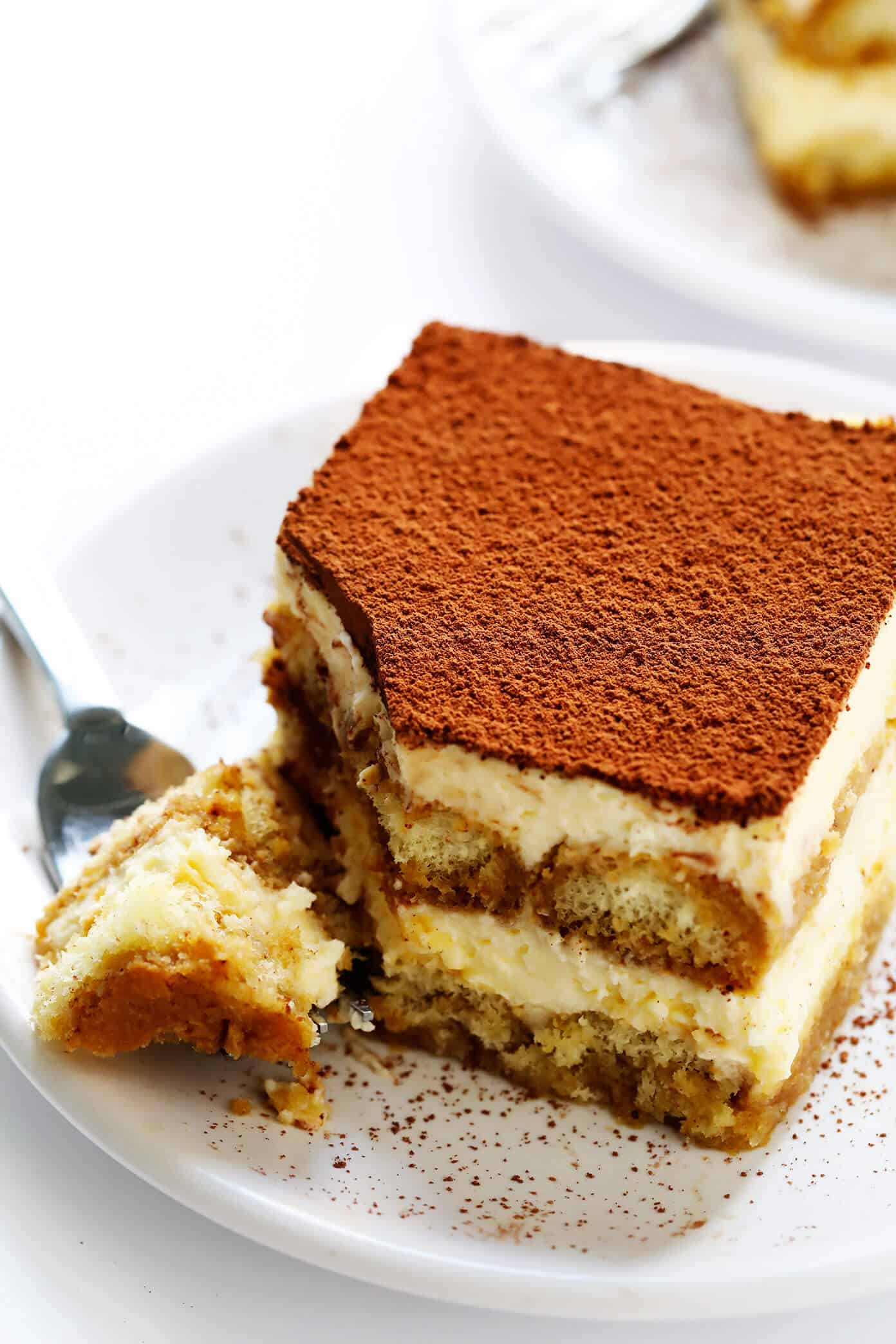 This tiramisu recipe is easy to whip up, this version is made with cooked (instead of raw) eggs, and it tastes just as indulgent and delicious as ever. The perfect make-ahead dessert for Italian night! | gimmesomeoven.com #tiramisu #italian #dessert #mascarpone #nobake #chocolate #vegetarian Italian tiramisu on serving plate