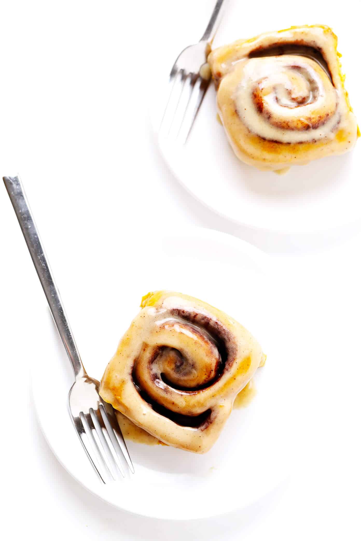 These pumpkin cinnamon rolls are perfectly delicious, soft, chewy and topped with a heavenly maple cream cheese frosting. Easy to make and ready to go in just around 1 hour! | gimmesomeoven.com #pumpkin #cinnamon #rolls #buns #breakfast #brunch #pumpkinspice #fall Individual Pumpkin Cinnamon Rolls on Plates with Forks
