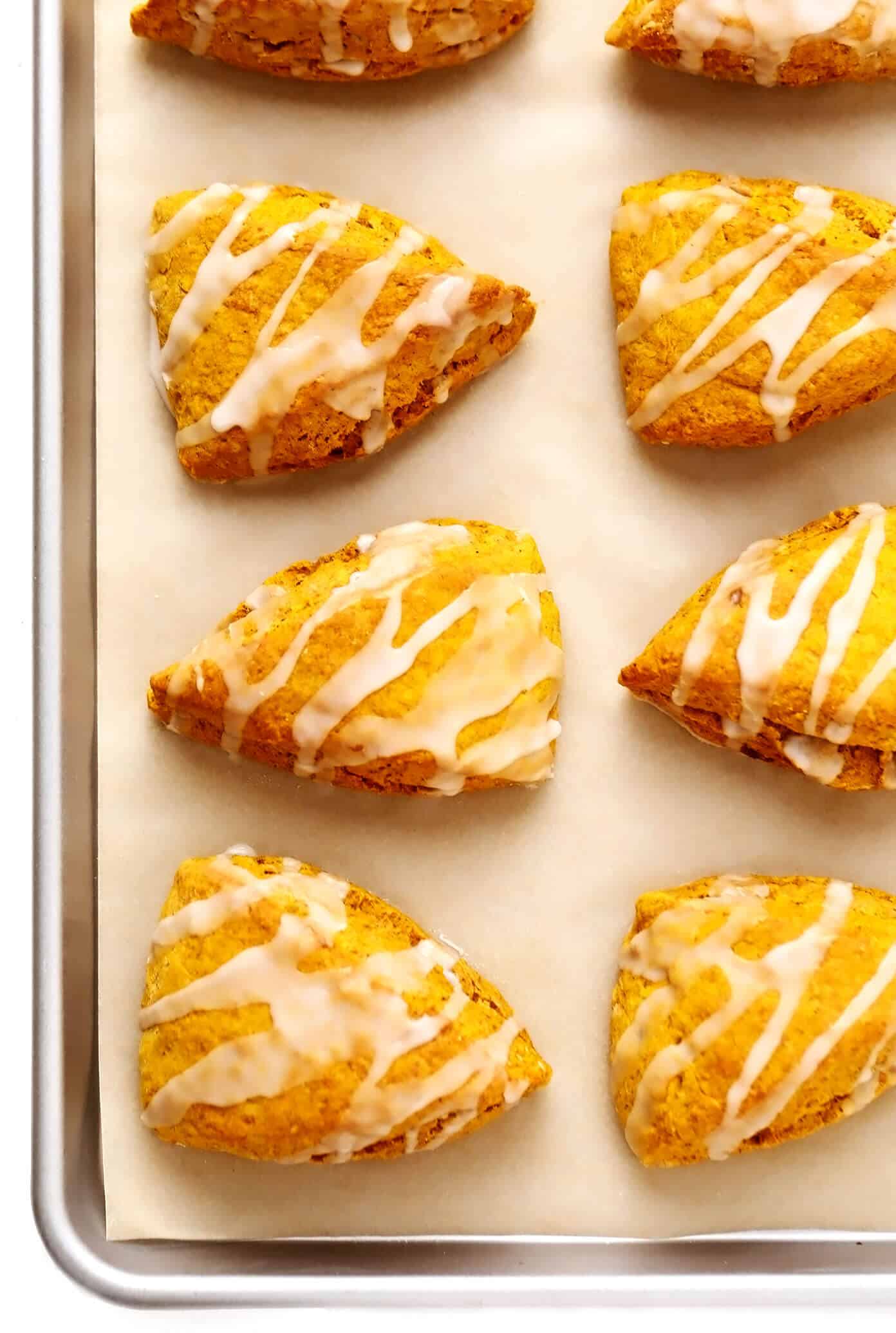 This pumpkin scones recipe is quick and easy to make, drizzled with a light vanilla glaze, and full of the best cozy pumpkin flavors. The perfect fall treat for breakfast, brunch, snack or dessert. | gimmesomeoven.com #pumpkin #scone #breakfast #brunch #dessert #treat #vanilla #glaze #icing #easy Pumpkin Scones on Baking Sheet